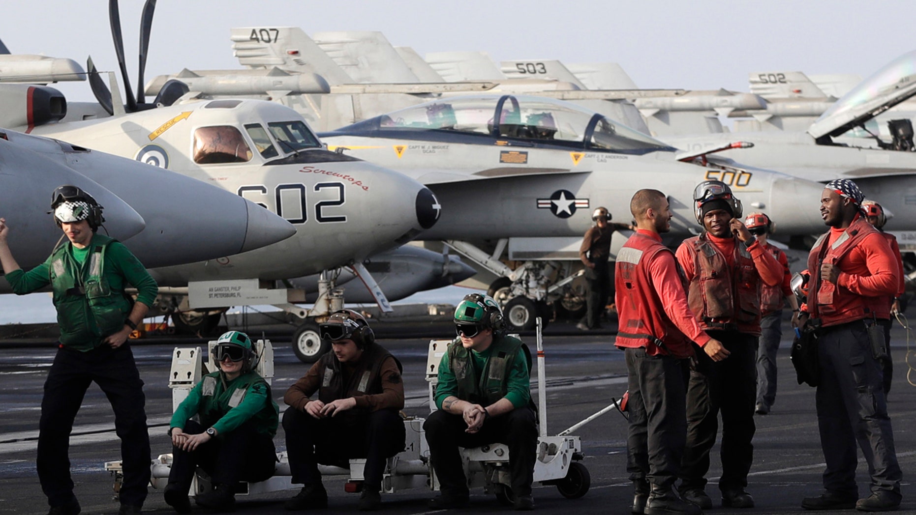 U.S. Navy sailors stand on the deck of the U.S.S. Dwight D. Eisenhower aircraft carrier on Tuesday, Nov. 22, 2016, U.S. Navy fighter jet takes off.