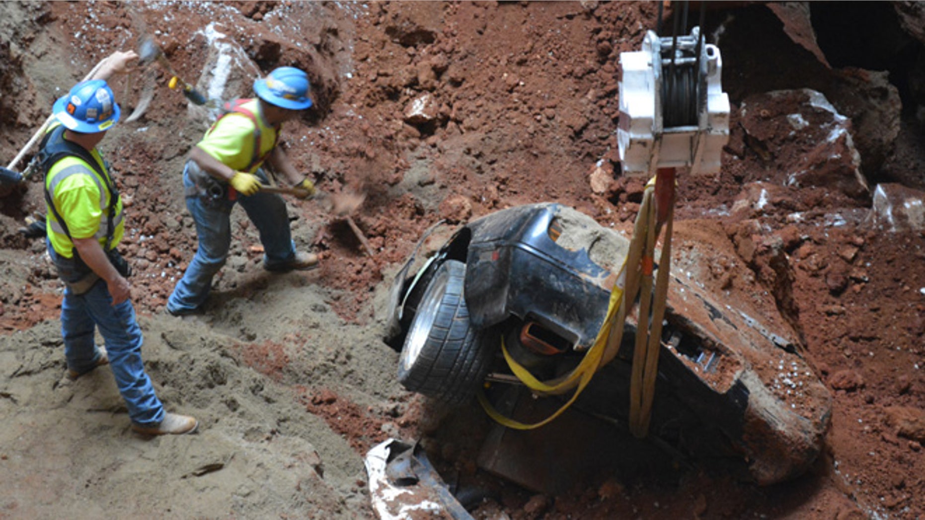In this undated photo provided by the National Corvette Museum, workers pull out a car from a sinkhole at the National Corvette Museum, in Bowling Green, Ky.