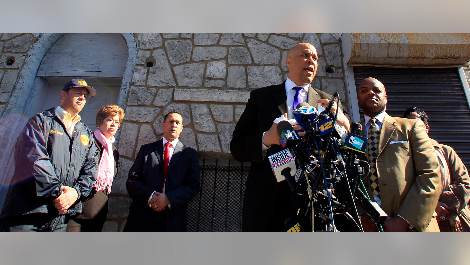 Newark Mayor Cory Booker talks about the fire in his next door neighbor's house in which he members of his security detail, including Alex Rodriguez, third from left, rescued residents from the burning building.