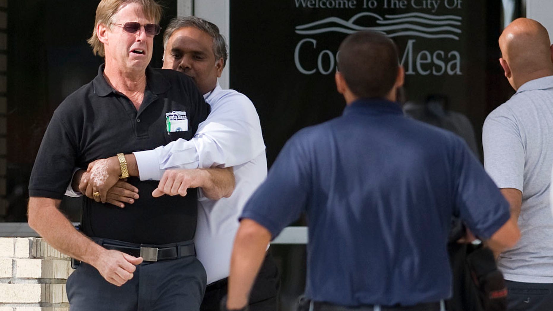 A city employee is held back by friends from confronting city managers at Costa Mesa City Hall after a maintenance worker jumped to his death Thursday, March 17, 2011 in Costa Mesa, Calif. (AP)