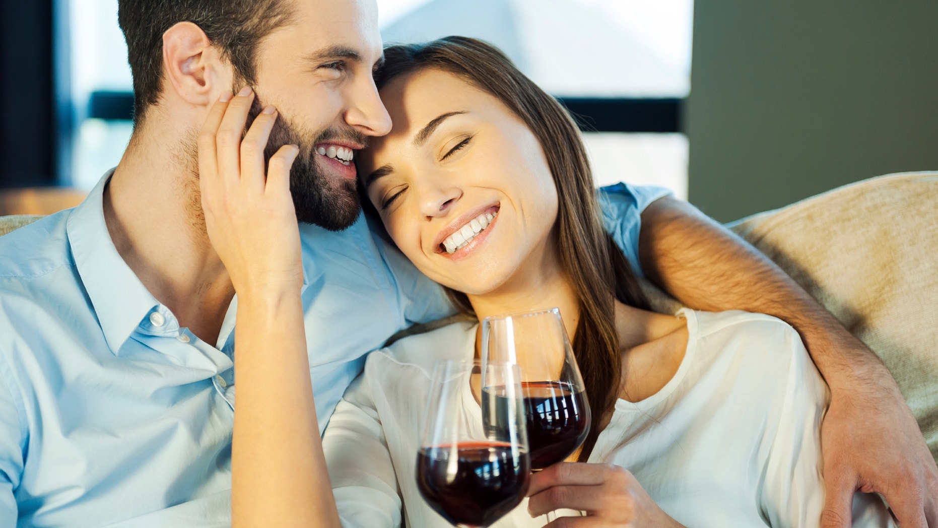 Love is a great feeling. Beautiful young loving couple sitting close to each other and drinking red wine
