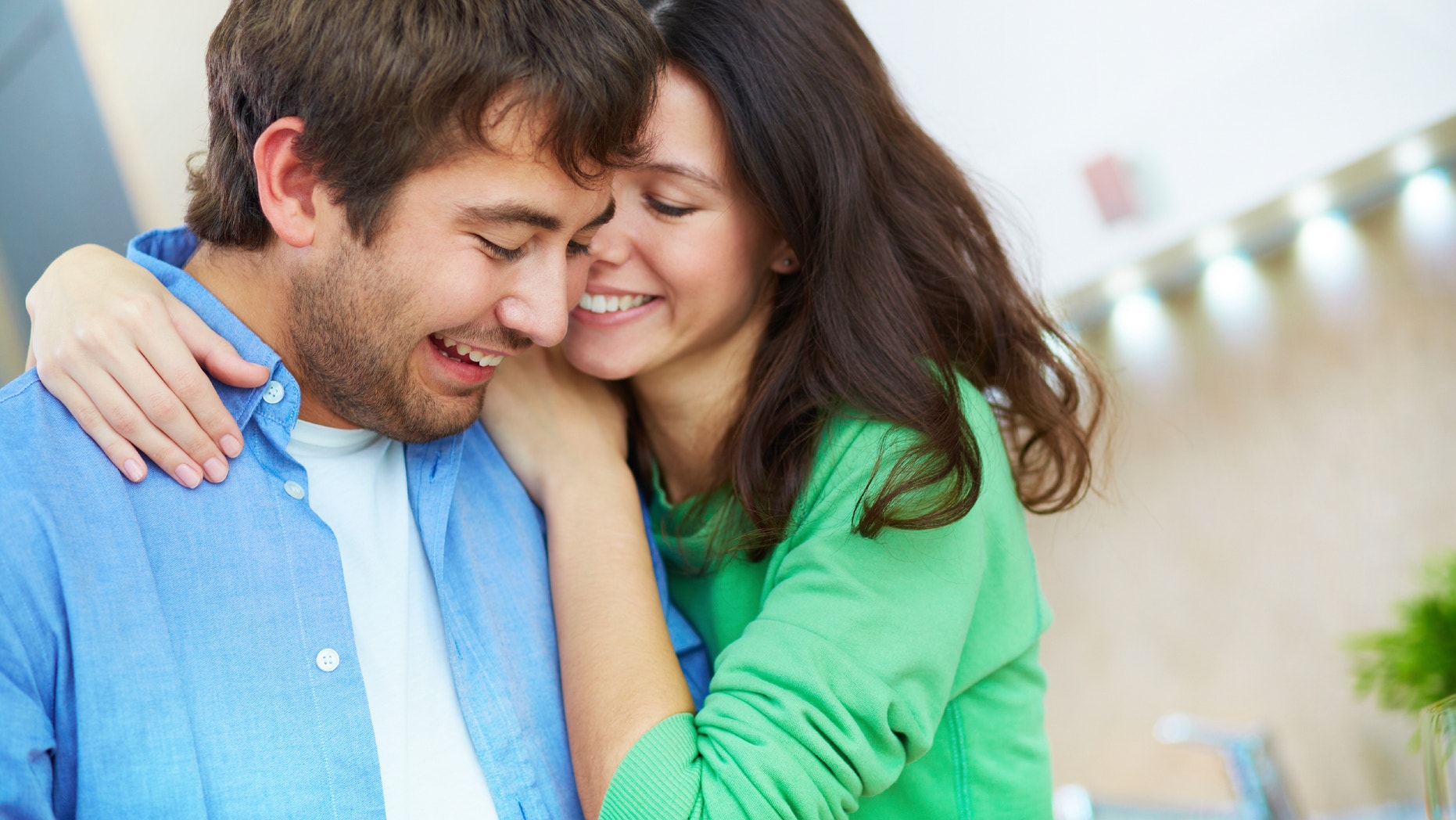 Portrait of young woman embracing her husband in the kitchen