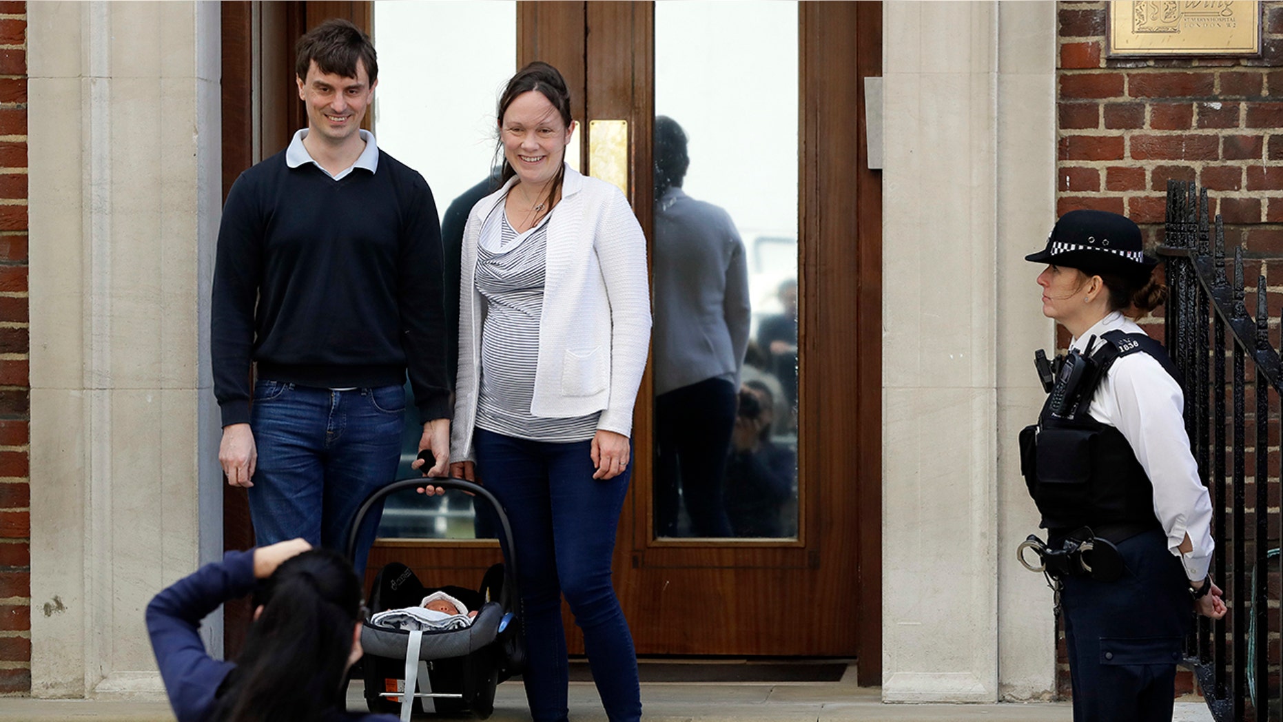 A couple pose for a photo with their newborn baby as they leave the Lindo wing at St Mary's Hospital in London London, Monday, April 23, 2018. Kensington Palace says Prince William's wife, the Duchess of Cambridge has entered a London hospital to give birth to the couple's third child. (AP Photo/Kirsty Wigglesworth)