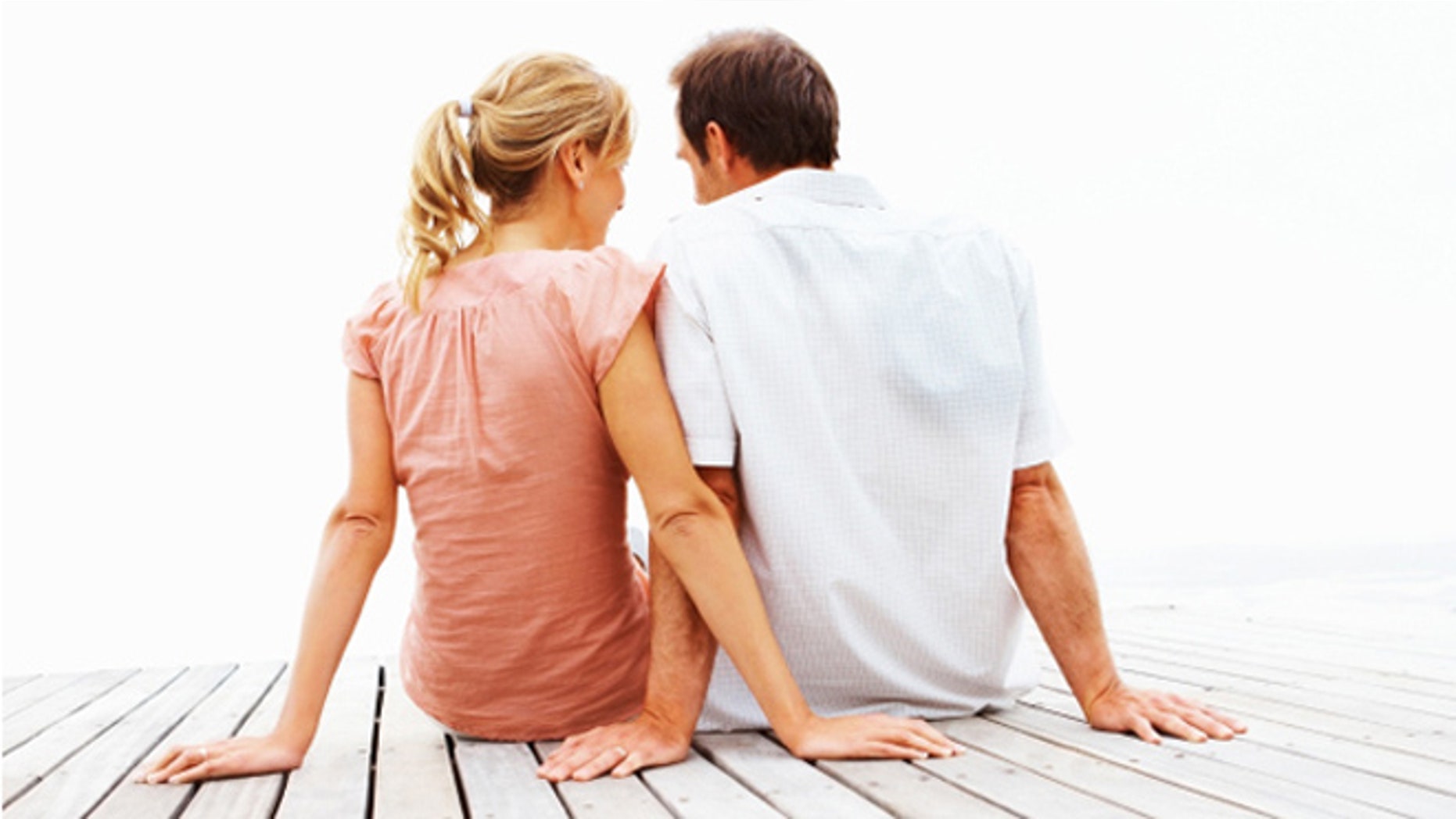 A romantic couple sitting on a jetty over white background