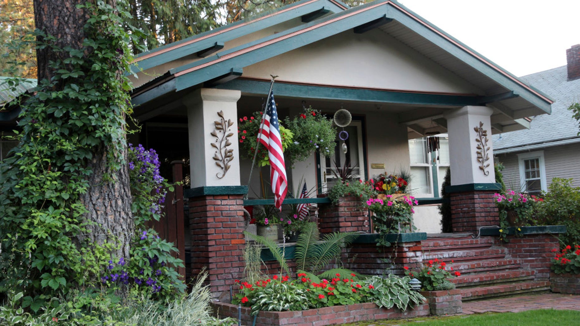 A Craftsman house displays the flag and flowers in front.