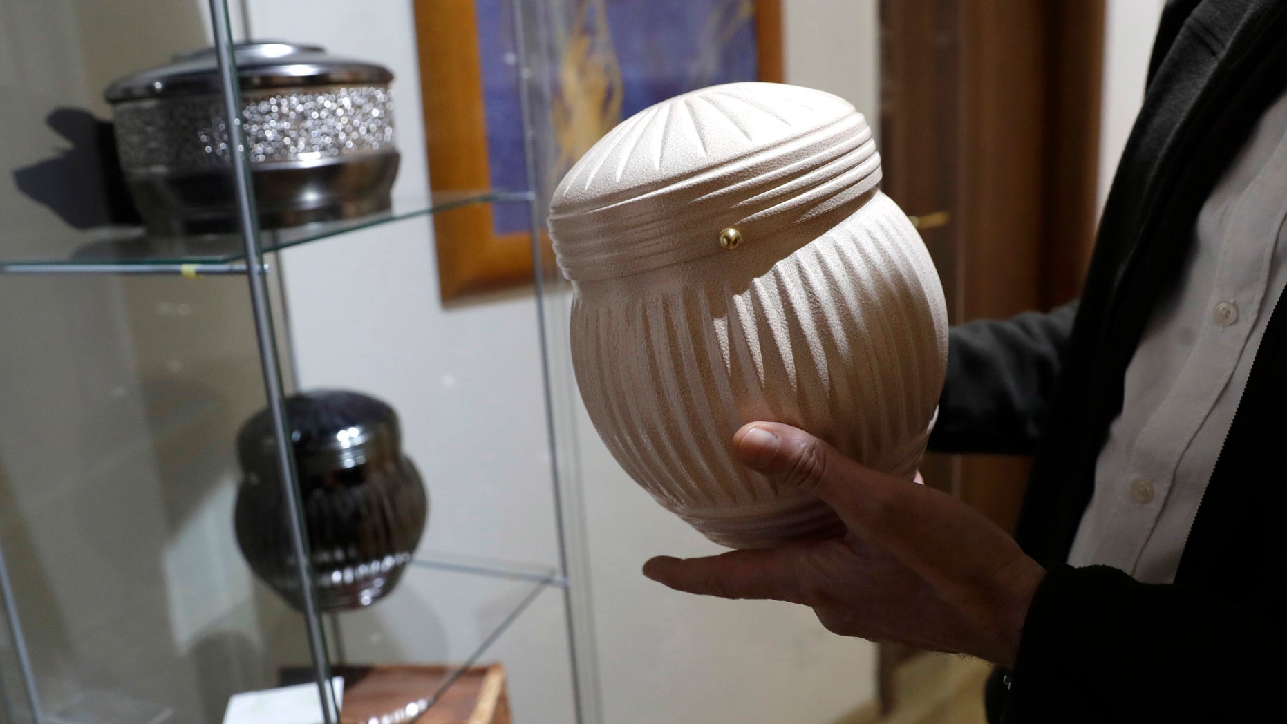 A man holds an urn at a funeral parlor in Rome, Tuesday, Oct. 25, 2016. The Vatican on Tuesday published guidelines for Catholics who want to be cremated, saying their remains cannot be scattered, divvied up or kept at home but rather stored in a sacred, church-approved place. (AP Photo/Alessandra Tarantino)