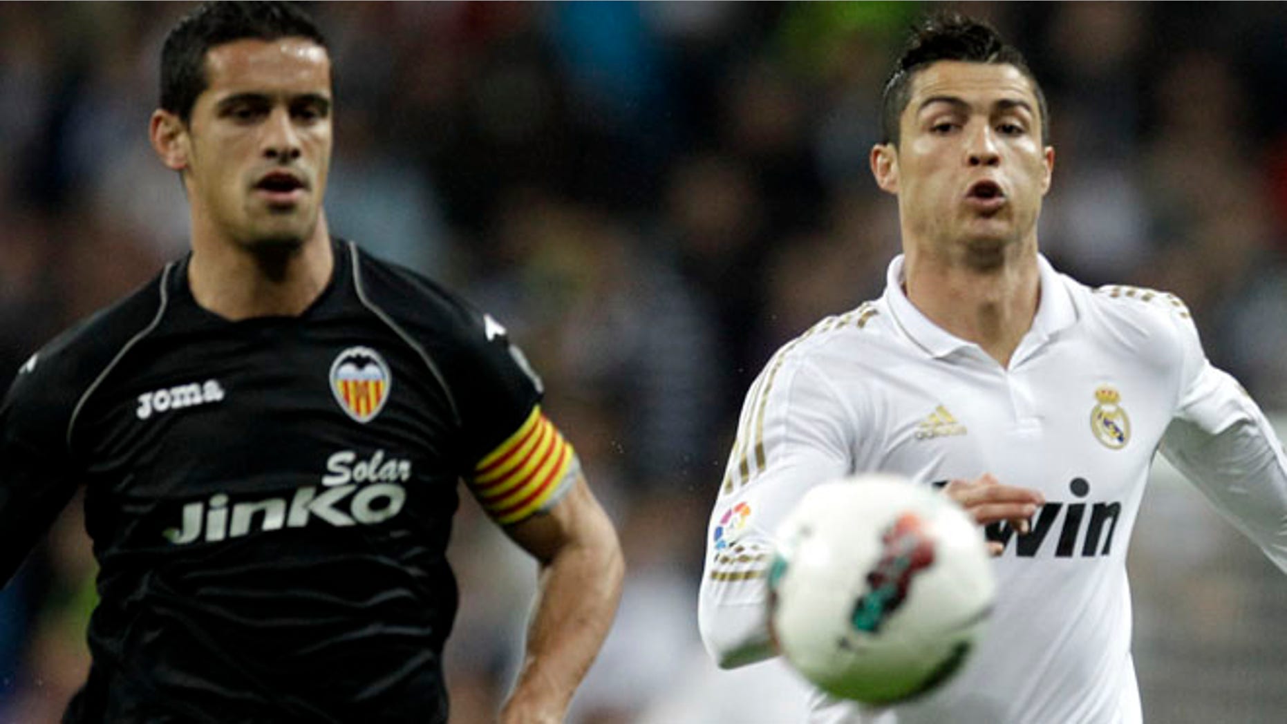 Real Madrid's Cristiano Ronaldo runs for the ball with Valencia's Ricardo Costa, Sunday April 8, 2012. (AP Photo/ Alberto Di Lolli )