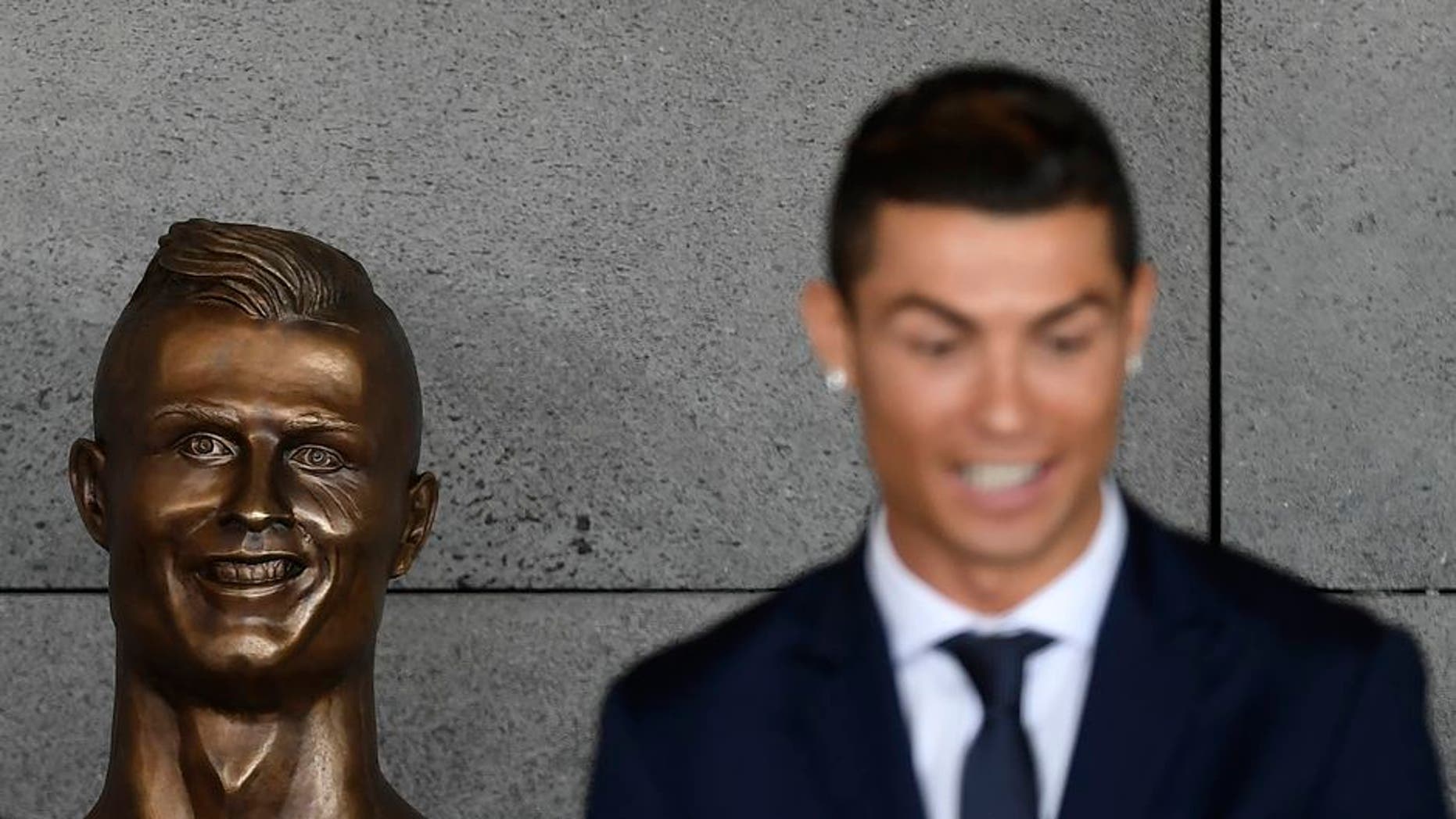 Portuguese footballer Cristiano Ronaldo stands beside a bust presented during a ceremony to rename Madeira's airport in Funchal as "Cristiano Ronaldo", on Madeira island, on March 29, 2017. Airport of Madeira, the birthplace of Portuguese footballer Cristiano Ronaldo, was renamed today in honor of the quadruple Ballon d'or and captain of the Portuguese team sacred European champion last summer. / AFP PHOTO / FRANCISCO LEONG (Photo credit should read FRANCISCO LEONG/AFP/Getty Images)