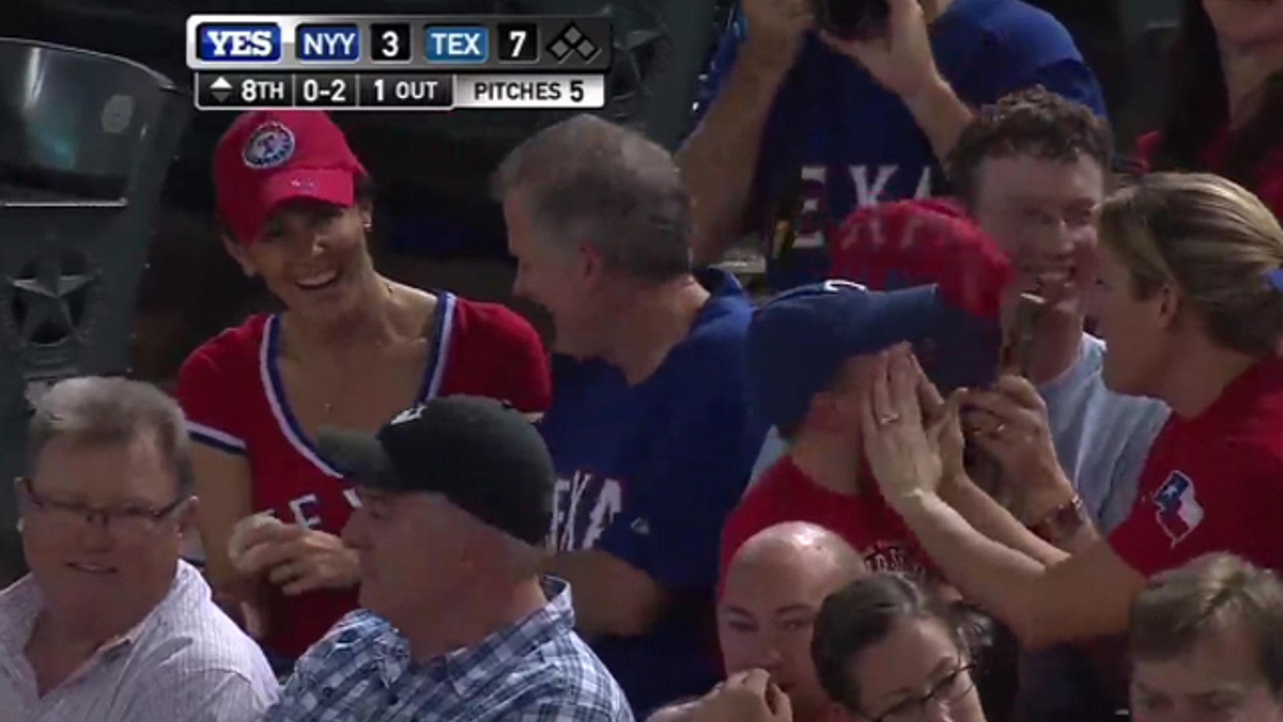 Shannon Moore, far left, and Sean Leonard celebrate catching a ball tossed into the stands during Wednesday's Rangers-Yankees game as 3-year-old Cameron Shores cries.