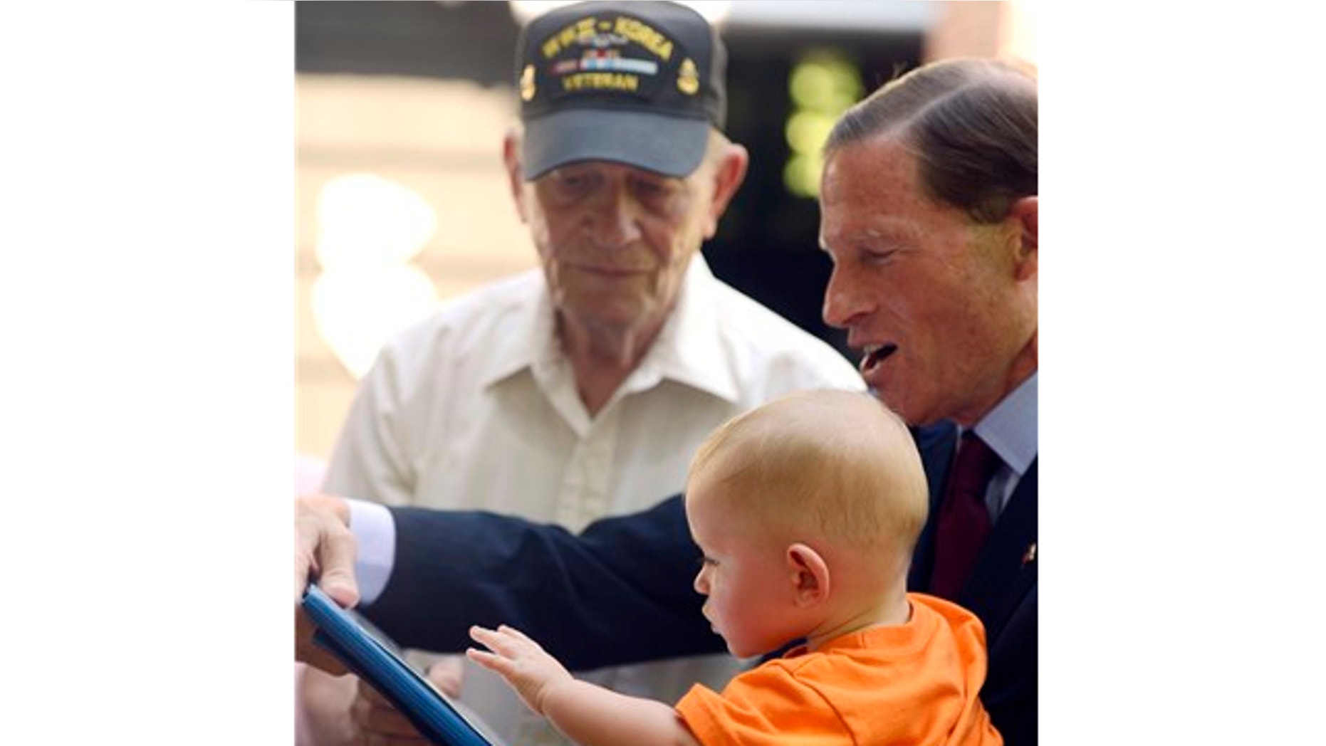 July 5, 2013: Sen. Richard Blumenthal, D-Conn., right, presents U.S. Navy WWII veteran Frank Bennett with a Purple Heart medal with 1-year old Axel Trygg Bennett at his home in Ledyard, Conn.