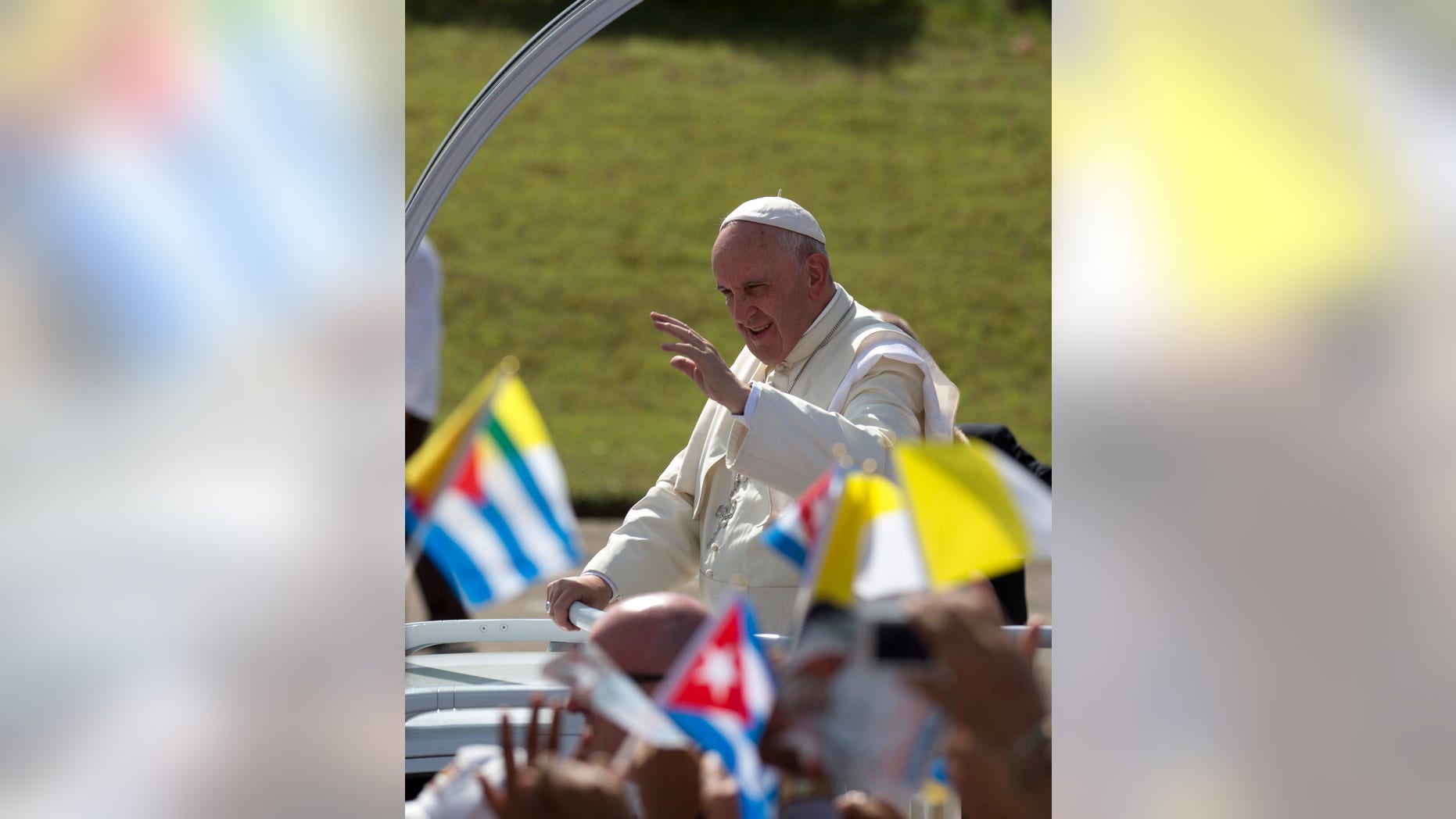Pope Francis waves from his popemobile as he arrives for Mass at the Plaza of the Revolution in Holguin, Cuba, Monday, Sept. 21, 2015. Holguin's plaza was packed with thousands of people waving flags as Francis traveled in his popemobile through the crowd. Francis is the first pope to visit Holguin, Cuba's third-largest city. (AP Photo/Eduardo Verdugo)