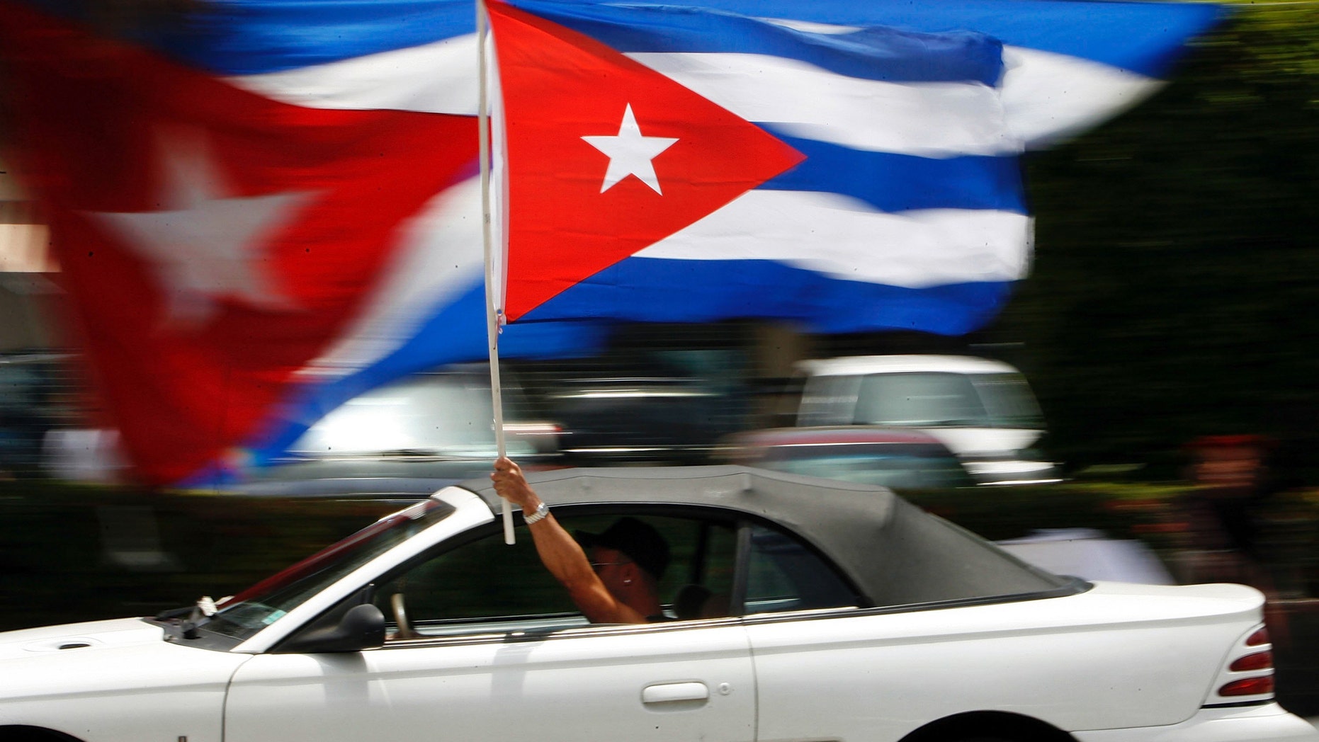 MIAMI - AUGUST 1: A motorist waves a Cuban flag while cruising down the famous Calle Ocho in the Little Havana neighborhood August 1, 2006 in Miami, Florida. Cuban Americans were celebrating the news that Fidel Castro had turned over power to his younger brother, Raul Castro, while he undergoes medical treatment for intestinal bleeding. (Photo by Chip Somodevilla/Getty Images)