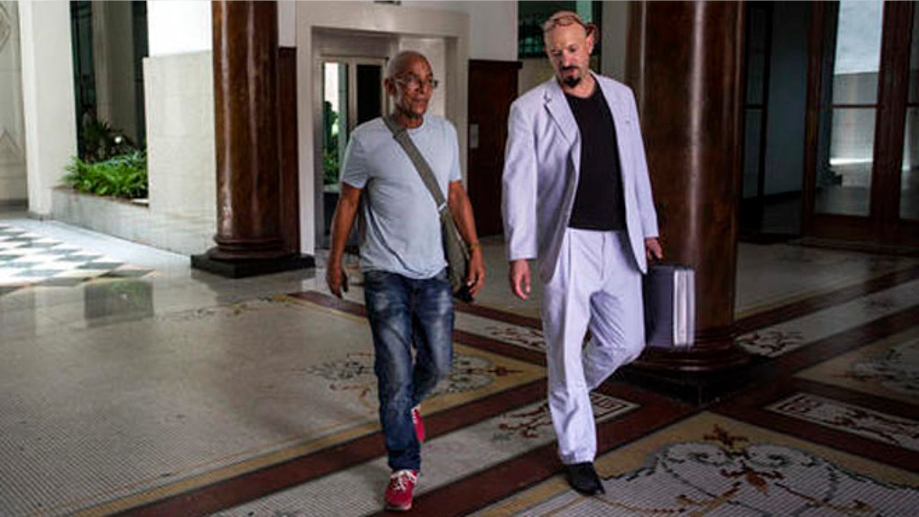 U.S. fugitive Charles Hill, left, walks with his lawyer Jason Flores Williams after an interview in Havana, Cuba, Friday, June 10, 2016. Hill, 66, who is sought in the 1971 killing of a New Mexico state policeman, told The Associated Press that Cuban contacts recently assured him he was at no risk of extradition. (AP Photo/Desmond Boylan)