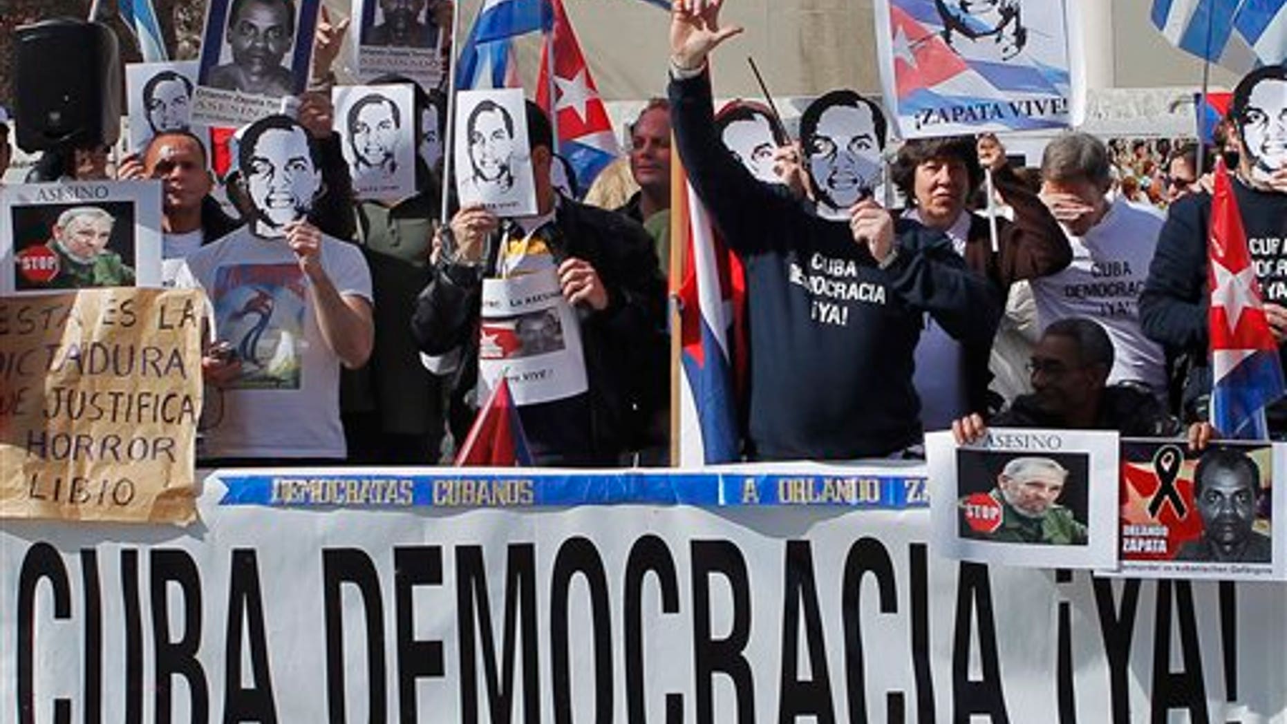 Cuban dissidents in Spain hold a banner reading: "Cuba democracy now!" during a rally outside the Cuban Embassy in Madrid Saturday Feb. 26, 2011. The protest marks the first anniversary of the death of Cuban dissident Orlando Zapata who died in Cuba after long hunger strike. (AP Photo/Andres Kudacki)