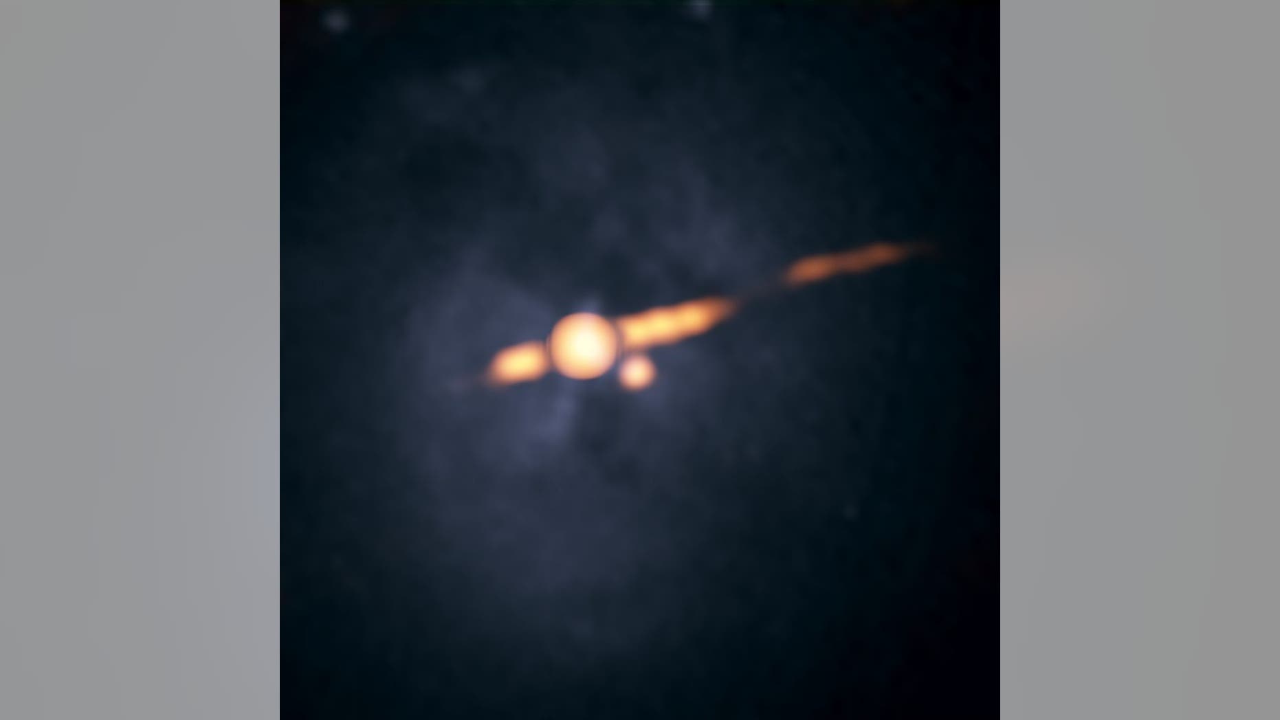 A radio image of the galaxy Cygnus A captured by the Very Large Array (VLA) in 2015 (orange), overlaid on a photo by NASA's Hubble Space Telescope. The orange dot below and to the right of the larger orange circle at the galaxy's center is the suspected second supermassive black hole.