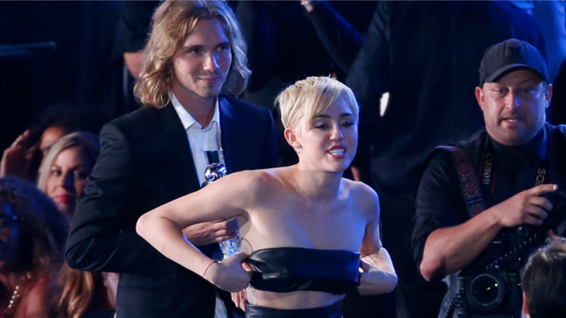 Miley Cyrus leaves with her spokesperson, named Jesse (L), after he accepted the award for video of the year for "Wrecking Ball" during the 2014 MTV Video Music Awards in Inglewood, California August 24, 2014. REUTERS/Lucy Nicholson (UNITED STATES - Tags: ENTERTAINMENT) (MTV-SHOW) - RTR43KLO