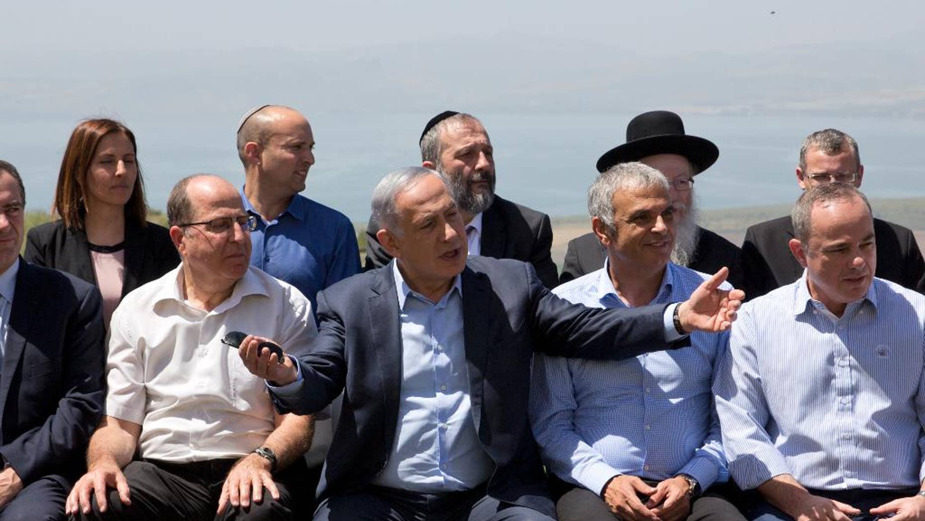 File - In this Sunday, April 17, 2016 file photo, Israeli Prime Minister Benjamin Netanyahu, center, poses with ministers prior to the weekly cabinet meeting in the Israeli controlled Golan Heights. Netanyahu has sparked a new diplomatic brushfire by declaring that the Golan Heights, seized from Syria in the 1967 war, is and should remain sovereign Israeli territory. But following some tough international criticism, Israeli officials have begun to backtrack, saying that a 1981 decision to apply Israeli law to the strategic plateau fell short of annexation and implying that Netanyahu misspoke. (AP Photo/Sebastian Scheiner, File)