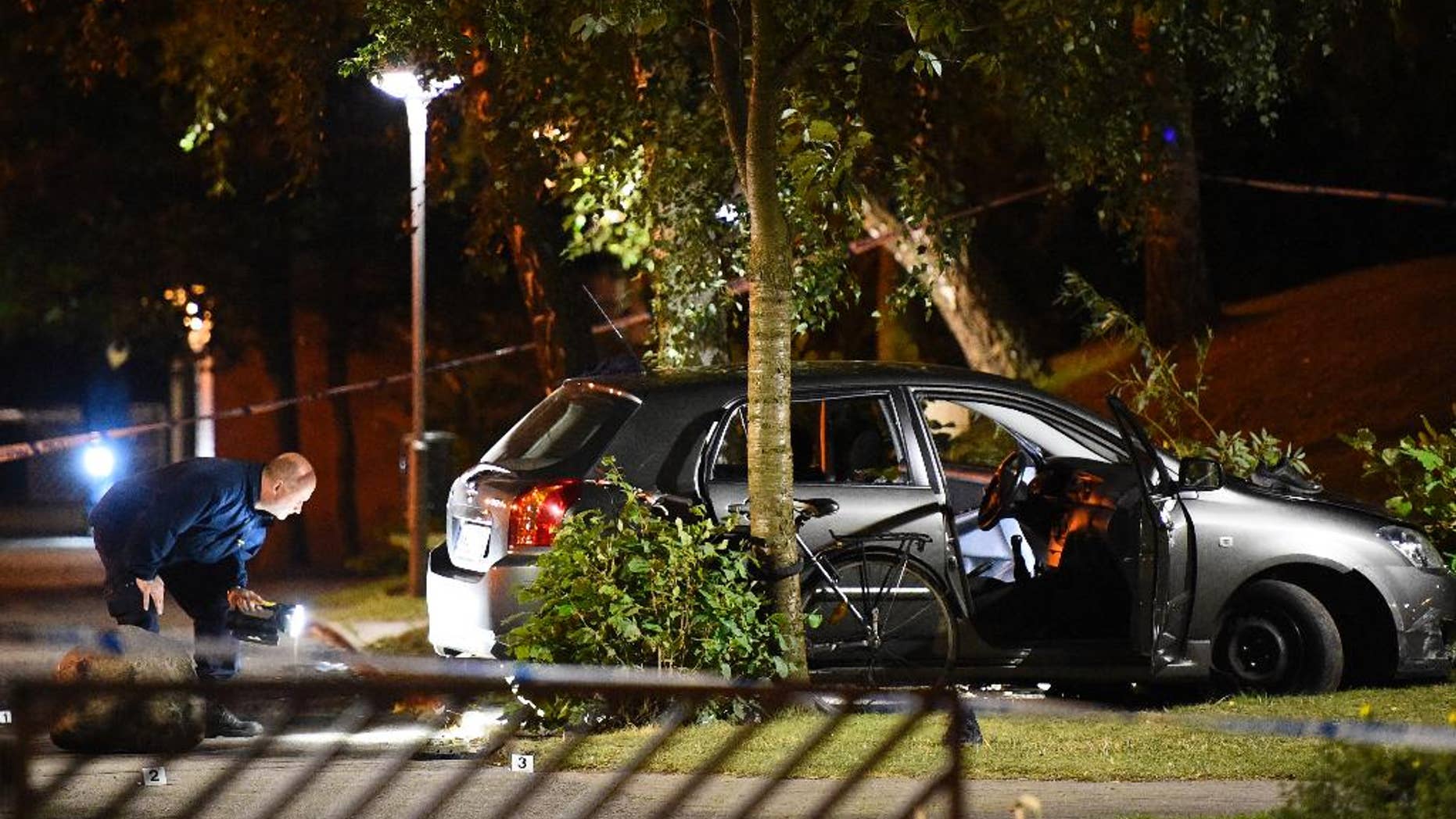 Police examine the scene of a shooting in southern Malmo, Sweden, Sunday Sept. 25, 2016. Swedish police say four people have been wounded in a shooting in Malmo, after gunmen on motor scooters opened fire Sunday evening on a car they had been chasing through a neighborhood. (Emil Langvad/TT via AP)