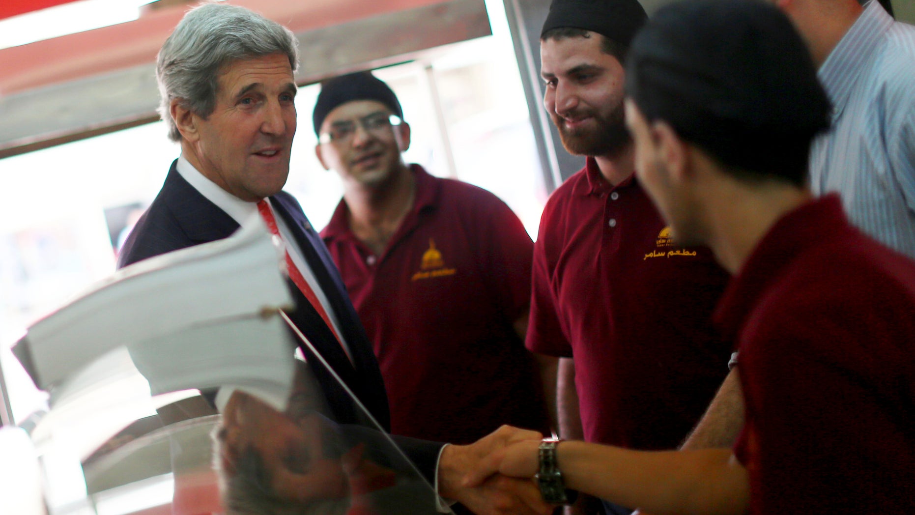 U.S. Secretary of State John Kerry shakea hands with Palestinian restaurant employees as he stops by for a snack after his meeting with Palestinian President Mahmoud Abbas in the West Bank city of Ramallah on Thursday, May 23, 2013. (AP Photo/Fadi Arouri, Pool)