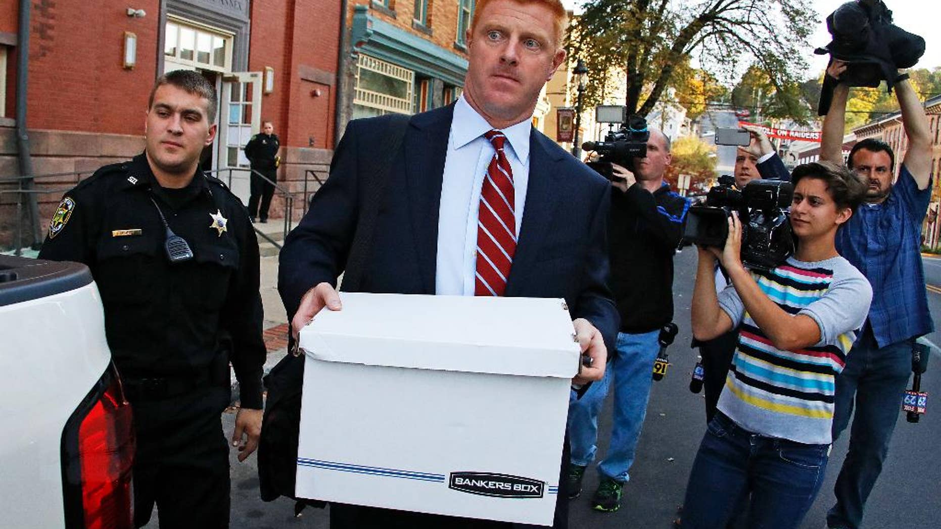 Former Penn State University assistant football coach Mike McQueary, center, leaves the Centre County Courthouse Annex in Bellefonte, Pa., Monday, Oct. 17, 2016. The trial for McQueary's defamation and whistleblower lawsuit against Penn State over how it treated him for complaining about assistant football coach Jerry Sandusky sexually abusing a boy got underway with opening arguments on Monday. (AP Photo/Gene J. Puskar)