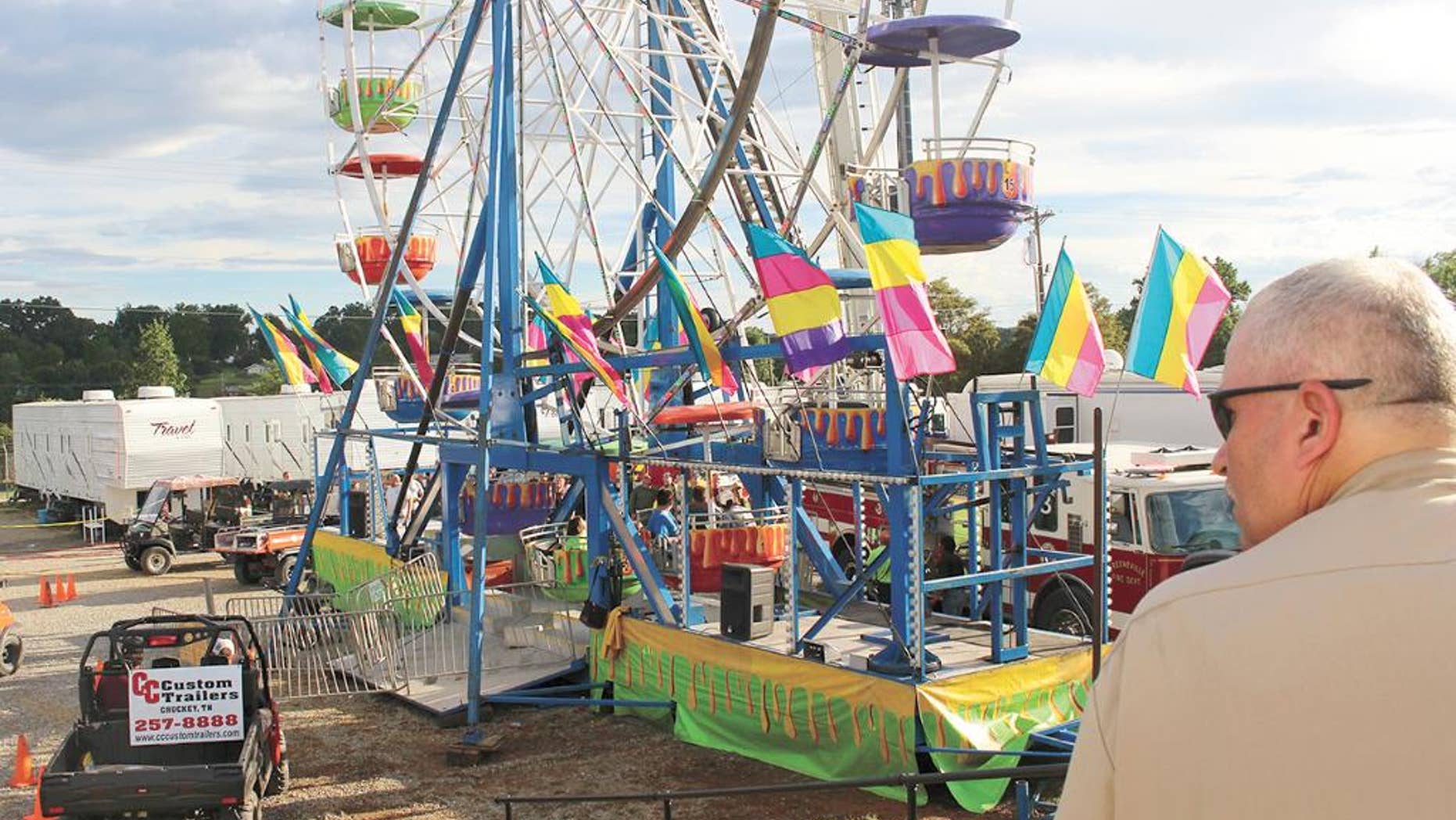 Law enforcement cordon off the area surrounding the Ferris wheel Monday, Aug. 8, 2016, after three people fell from the ride during a county fair in Greenville, Tenn. Baileyton police Officer Kenneth Bitner is visible at right. Police say one of three people who fell from the Ferris wheel suffered a head injury and remains hospitalized in serious condition. (O.J. Early/The Greeneville Sun via AP)