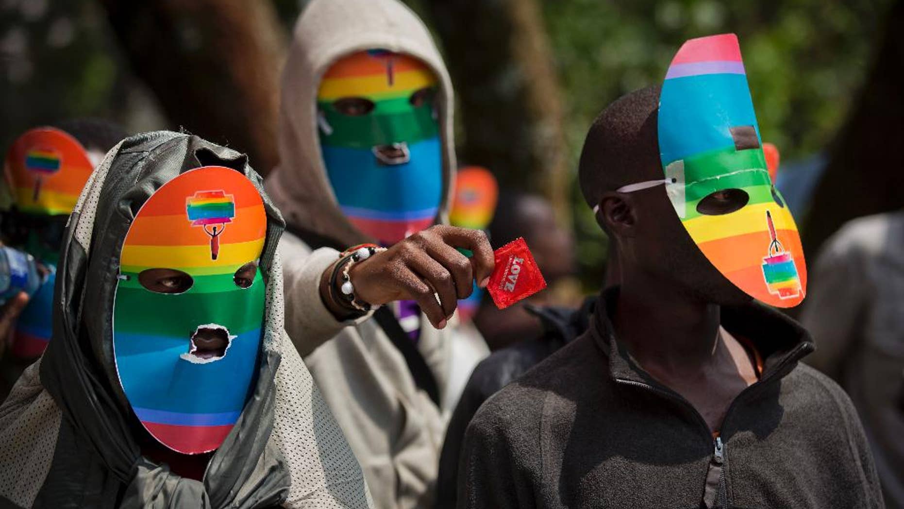 FILE - In this Monday, Feb. 10, 2014 file photo, Kenyan gays and lesbians and others supporting their cause wear masks to preserve their anonymity and one holds out a wrapped condom, as they stage a rare protest, against Uganda's increasingly tough stance against homosexuality and in solidarity with their counterparts there, outside the Uganda High Commission in Nairobi, Kenya. A Kenyan judge on Thursday, June 16, 2016 has upheld the use of enforced anal examinations to determine a suspect's sexual orientation, saying he found no violation of rights or the law and dismissed the petition by two men who were subjected to the procedures. (AP Photo/Ben Curtis, File)