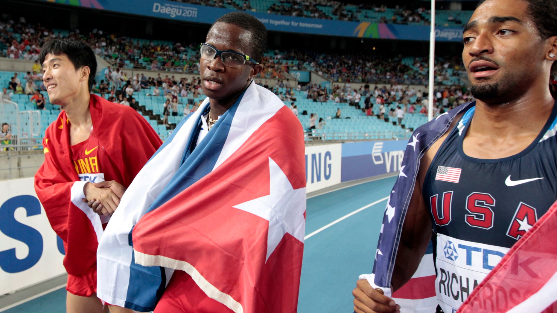 Aug. 29: Cuba's Dayron Robles, center, walks with Cuban flag, after crossing the finish line first in the Me'n's 110m Hurdles final at the World Athletics Championships in Daegu, South Korea. Robles finished first but was later disqualified for making contact with China's Liu Xiang, left.