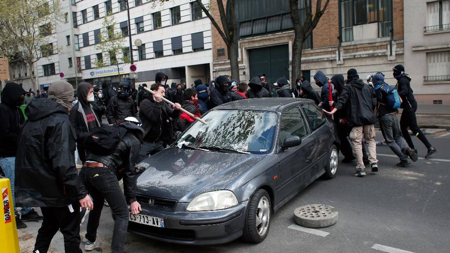 Protestors damage a car during clashes with riot police officers as part of a demonstration against the proposed changes to France's working week and layoff practices, in Paris, Thursday, April 28, 2016. Protesters across France are again marching to voice their anger at labor reforms being championed by the country's Socialist government. (AP Photo/Thibault Camus)
