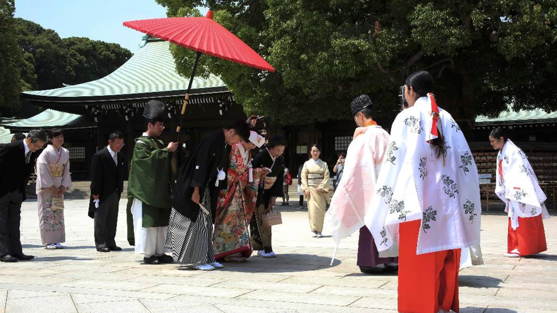 FILE - In this May 27, 2015 file photo, a newlywed couple, center, bows to a Shinto priest, third from right, in the compound of Meiji Jingu Shrine after their Japanese traditional wedding ceremony in Tokyo. In Japan, every marriage costs one surname. The Supreme Court may change that on Wednesday, Dec. 16, 2015. A Civil Code that dates from the 19th century says couples must adopt one surname, and women almost always sacrifice theirs. Five plaintiffs filed a lawsuit in 2011 saying the law is unconstitutional, violates their civil rights and puts the burden almost entirely on women. Two lower courts have ruled against them, setting the stage for Wednesday’s Supreme Court ruling. (AP Photo/Eugene Hoshiko, File)