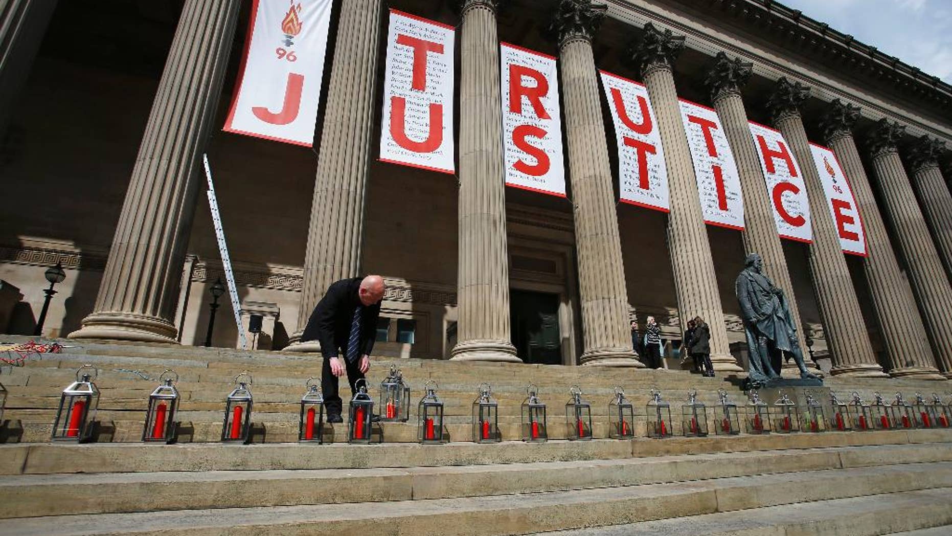 A man places candles for each of the 96 Liverpool fans who died as a result of the Hillsborough disaster at St George's Hall in Liverpool, England, Wednesday, April 27, 2016. Liverpool is commemorating the deaths of 96 soccer fans crushed to death in a crowded stadium in 1989 after a jury found that blunders by police and emergency services contributed to their deaths. (Peter Byrne/PA via AP) UNITED KINGDOM OUT