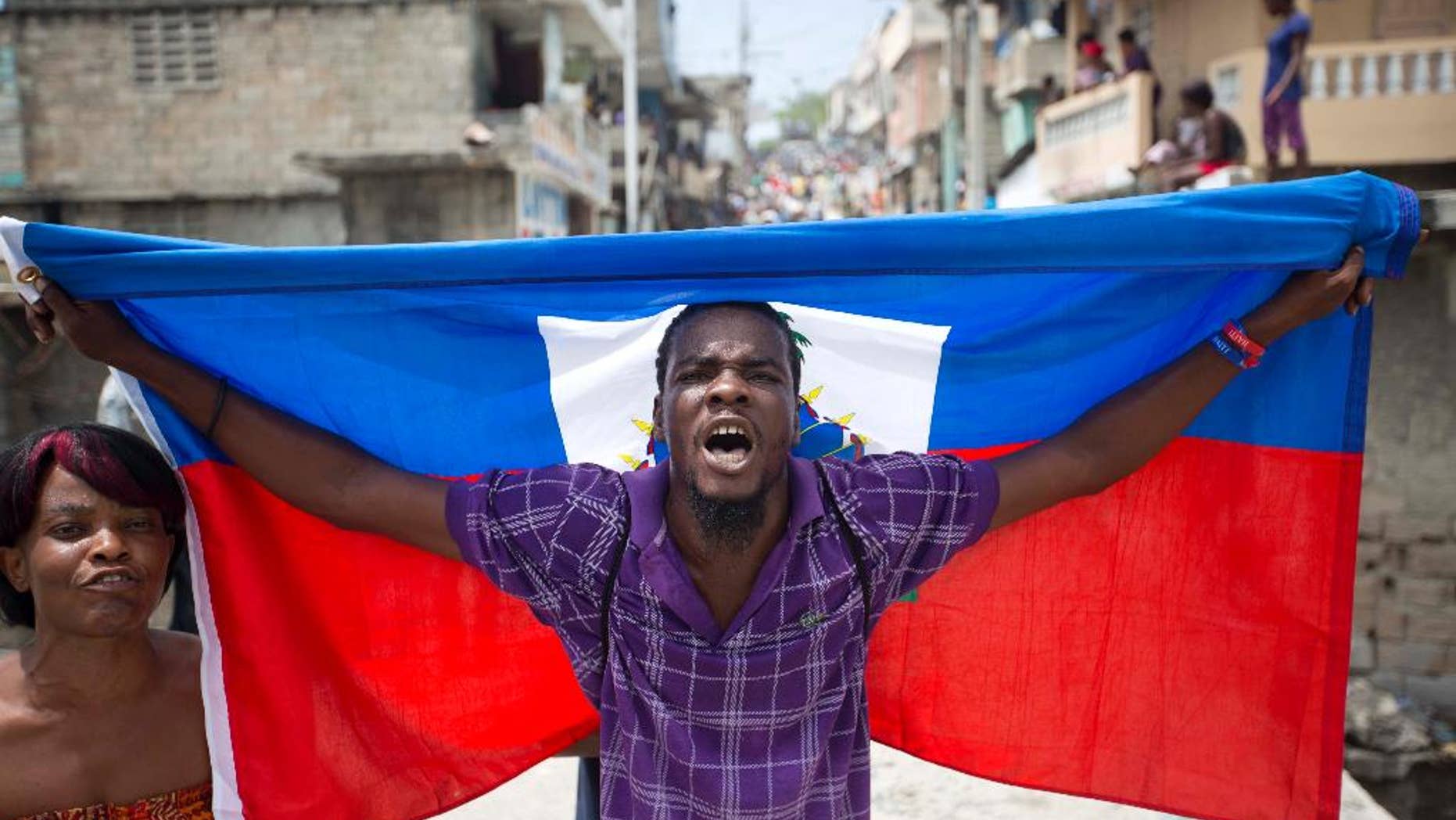 A supporter of presidential candidate Maryse Narcisse marches with a Haitian national flag during a demonstration in support of interim President Jocelerme Privert in Port-au-Prince, Haiti, Tuesday, June 14, 2016. Haiti's legislators will decide whether to pave way for a new interim leader until elections can be resolved or extend the term for Privert, whose 120-day mandate is due to expire today. ( AP Photo/Dieu Nalio Chery)