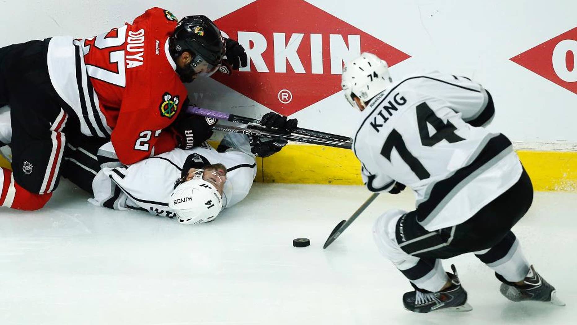 Los Angeles Kings left wing Dwight King (74) takes the puck as Chicago Blackhawks defenseman Johnny Oduya (27) and the Kings right wing Justin Williams (14) battle during the overtime period in Game 5 of the Western Conference finals in the NHL hockey Stanley Cup playoffs Wednesday, May 28, 2014, in Chicago. (AP Photo/Andrew A. Nelles)