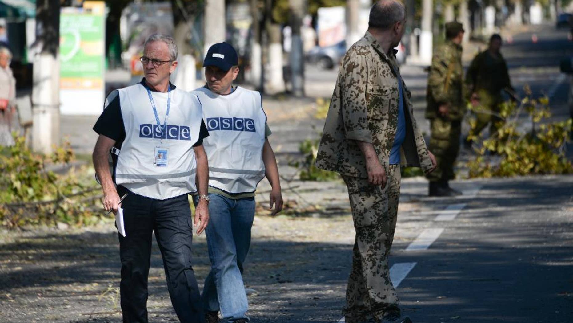 Members of the OSCE examine the scene of a shelling in the town of Donetsk, eastern Ukraine, Wednesday, Aug. 27, 2014. The Obama administration accused Russia on Wednesday of orchestrating a new military campaign in Ukraine, helping rebel forces expand their fight in the country's east and sending tanks, rocket launchers and armored vehicles toward communities elsewhere. (AP Photo/Mstislav Chernov)