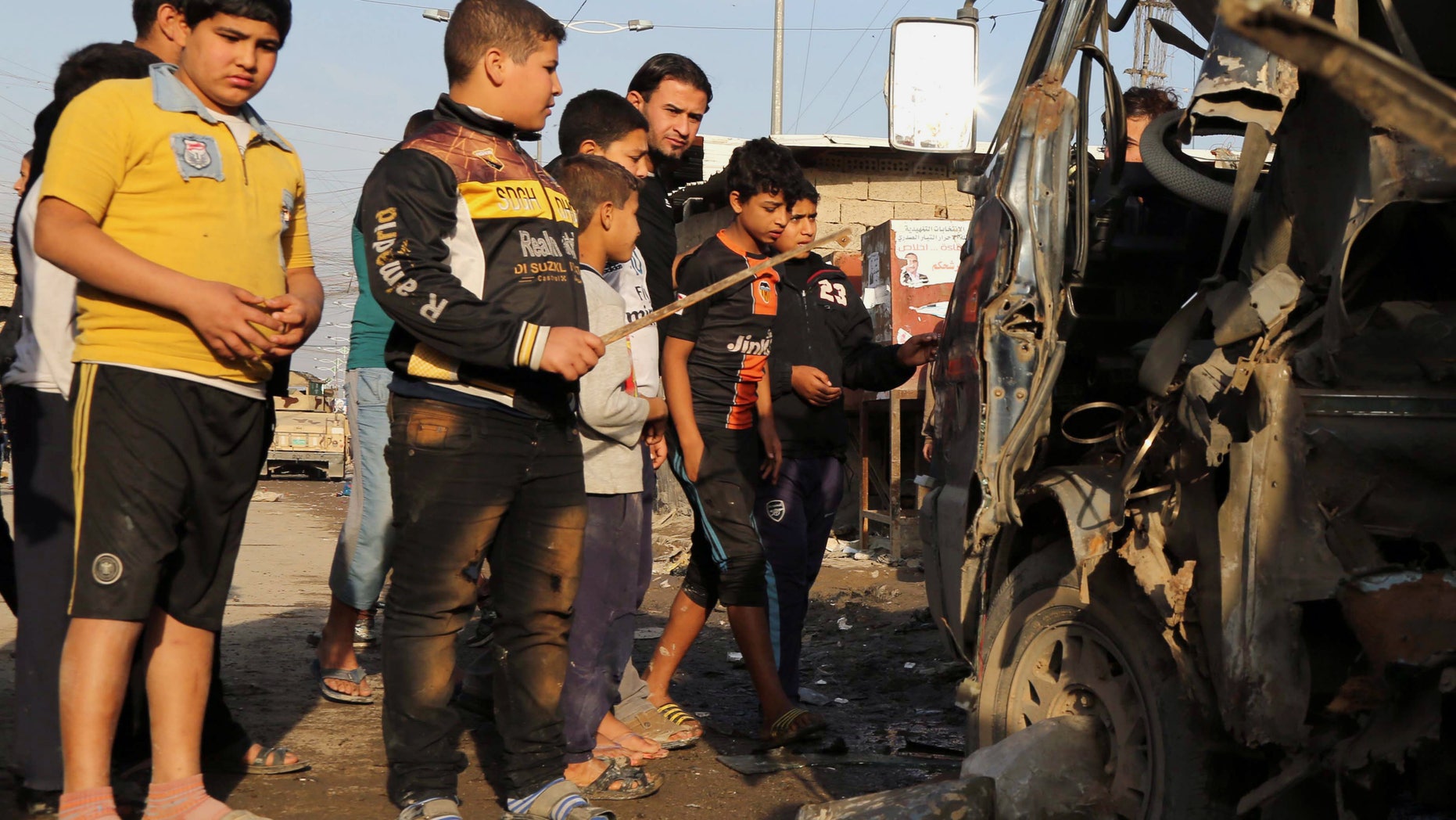 Citizens inspect the site of a car bomb attack in Sadr City neighborhood in Baghdad, Iraq, Sunday, Dec. 8, 2013. Officials in Iraq say scores have been killed in at least 11 explosions tore through predominantly Shiite Muslim areas in and around the Iraqi capital on Sunday. (AP Photo/Karim Kadim)