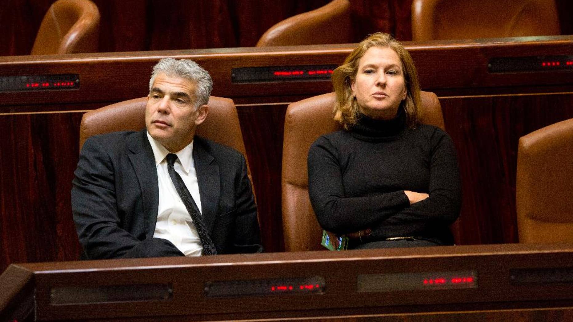 Israeli Finance Minister Yair Lapid, left, and Justice Minister Tzipi Livni sit following a vote at the Knesset, Israel's parliament in Jerusalem, Wednesday, Dec. 3, 2014. Israeli lawmakers voted Wednesday to dissolve the Knesset, a preliminary step that will pave the way for early elections two years ahead of schedule. (AP Photo/Sebastian Scheiner)