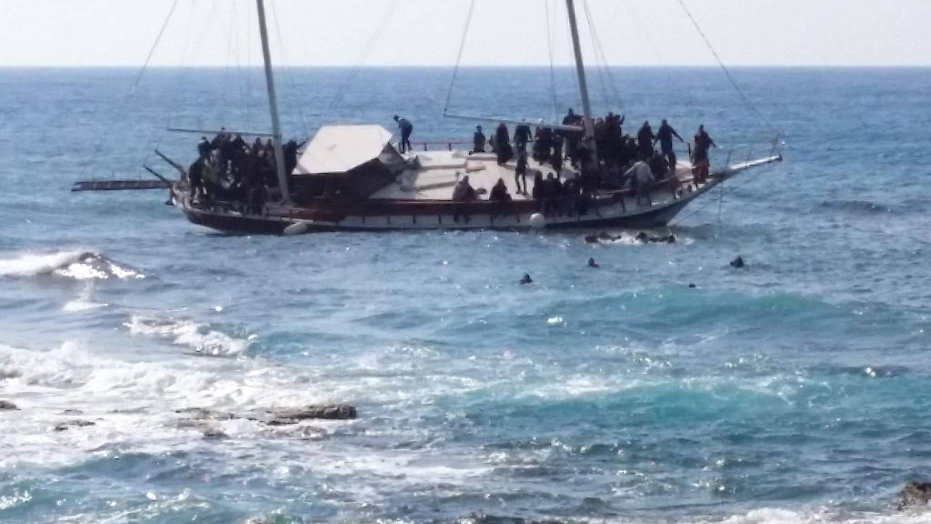 Migrants swim to reach the shore as others remainare on a listing vessel that later sunk in the eastern Aegean island of Rhodes, Greece on Monday, April 20, 2015. Greek authorities said that at least three people have died, including a child, after a wooden boat carrying tens of migrants ran aground off the island of Rhodes. (AP Photo/Michalis Loizos) GREECE OUT