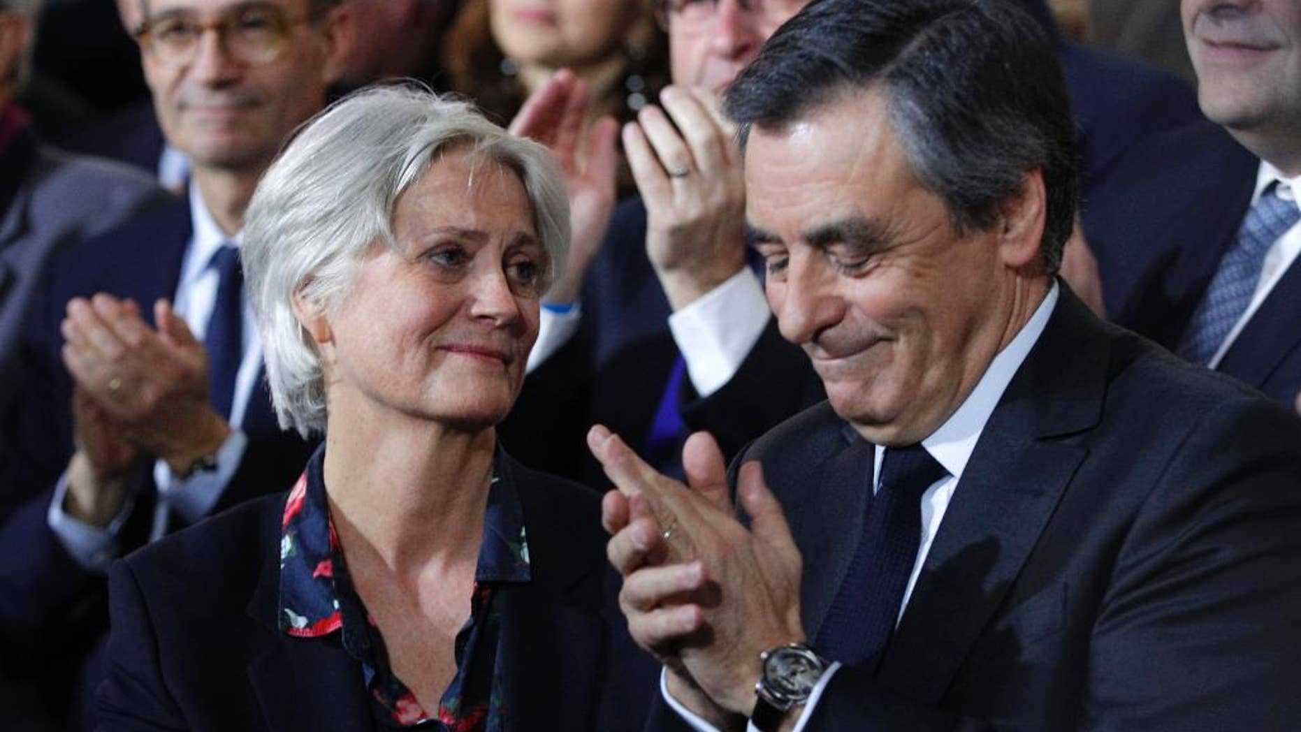 Conservative presidential candidate Francois Fillon applauds while his wife Penelope looks on as they attend a campaign meeting in Paris, Sunday, Jan. 29, 2017. Financial prosecutors are investigating an allegedly fake but handsomely paid job held by the former prime minister's wife, Penelope. (AP Photo/Christophe Ena)