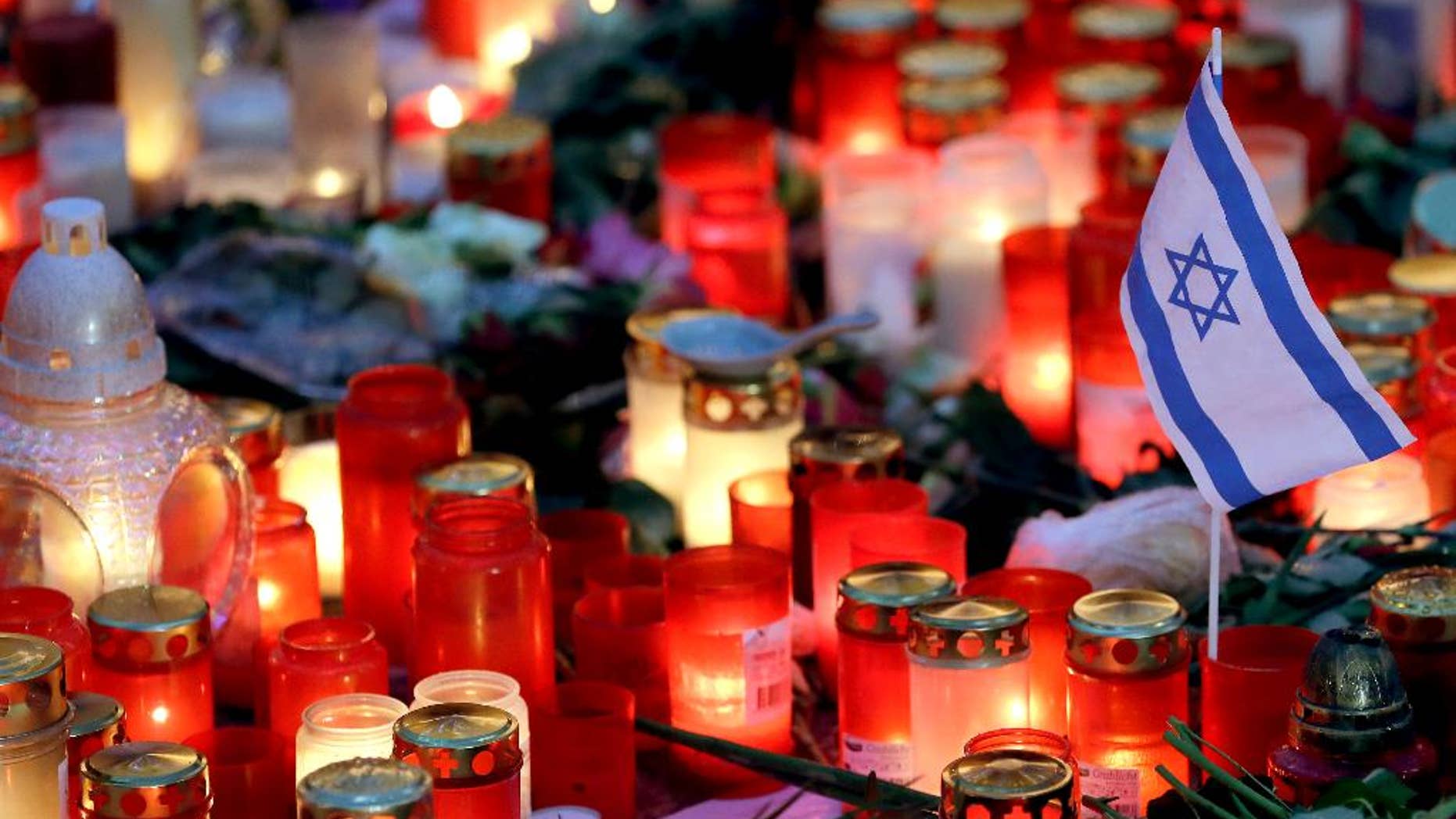 A small flag of Israel is pictured between candles and flowers after the reopening of the Christmas market at the Kaiser Wilhelm Memorial Church in Berlin, Germany, Thursday, Dec. 22, 2016 three days after a truck ran into the crowded market and killed several people. (AP Photo/Michael Sohn)