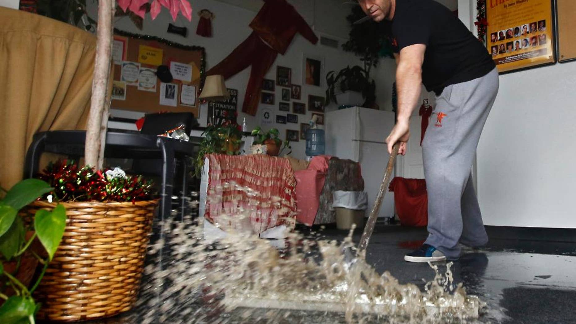 FILE - In this Jan. 5, 2016, file photo, Chris Lene sweeps water out of one of the businesses in the building he owns that was flooded by rainwater in Sacramento, Calif. Federal meteorologists proclaimed the end of the super-sized El Nino that further heated up the globe, but didn’t quite end California’s four year drought. The National Oceanic and Atmospheric Administration Thursday, June 9, 2016, said the El Nino has ended, 15 months after its birth in March 2015. El Nino is a natural warming of parts of the central Pacific that changes weather worldwide. (AP Photo/Rich Pedroncelli, File)