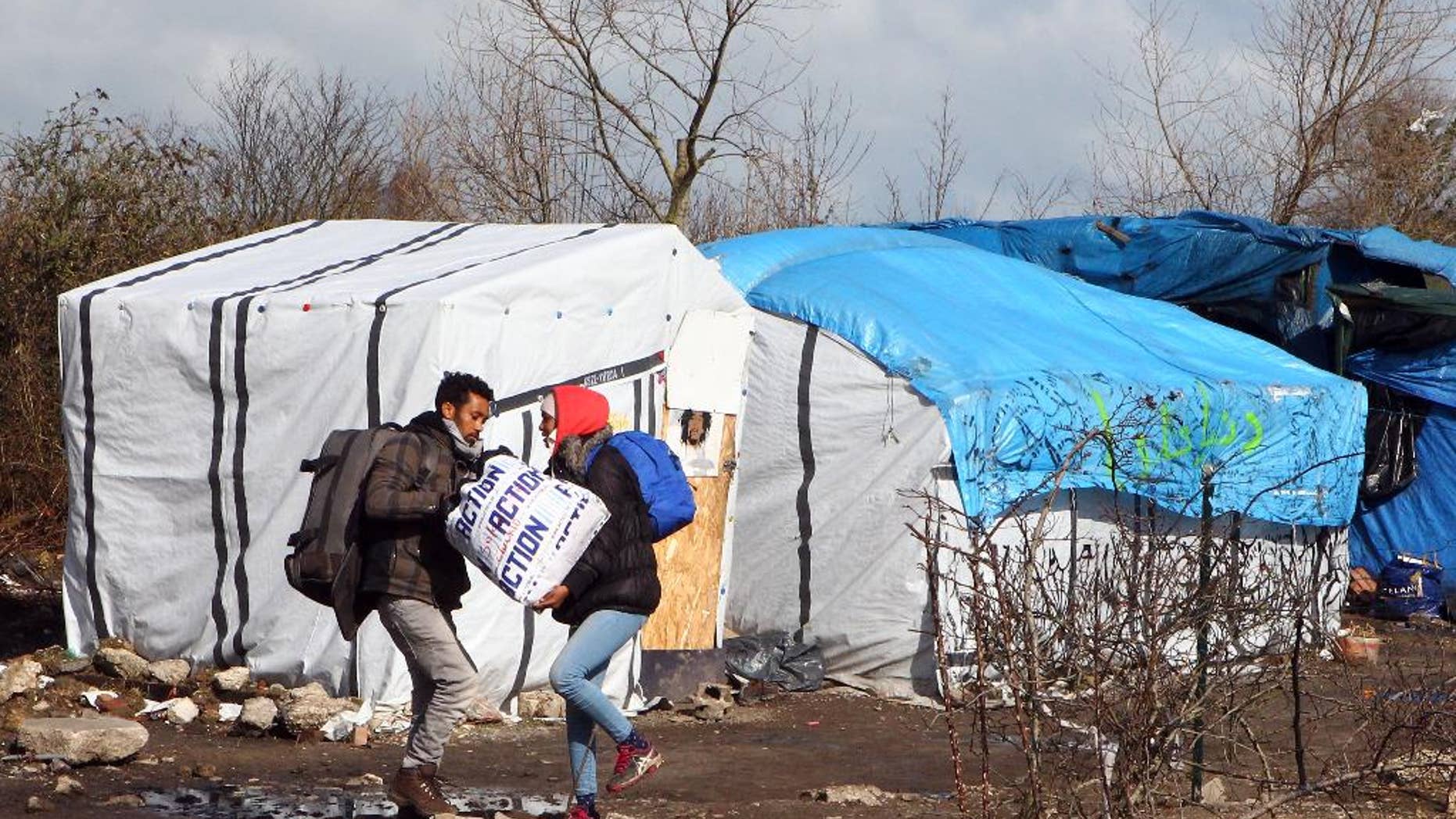 FILE - In this Thursday, March 3, 2016 file photo, unidentified migrants leave the makeshift camp near Calais, France. Residents of Champtercier fear their hamlet in the foothills of the Alps is about to become a new flashpoint for Europe’s migrant crisis: Its population of 800 is slated to grow sharply when it takes in 100 migrants from an overflowing camp in Calais next month. (AP Photo/Michel Spingler, File)