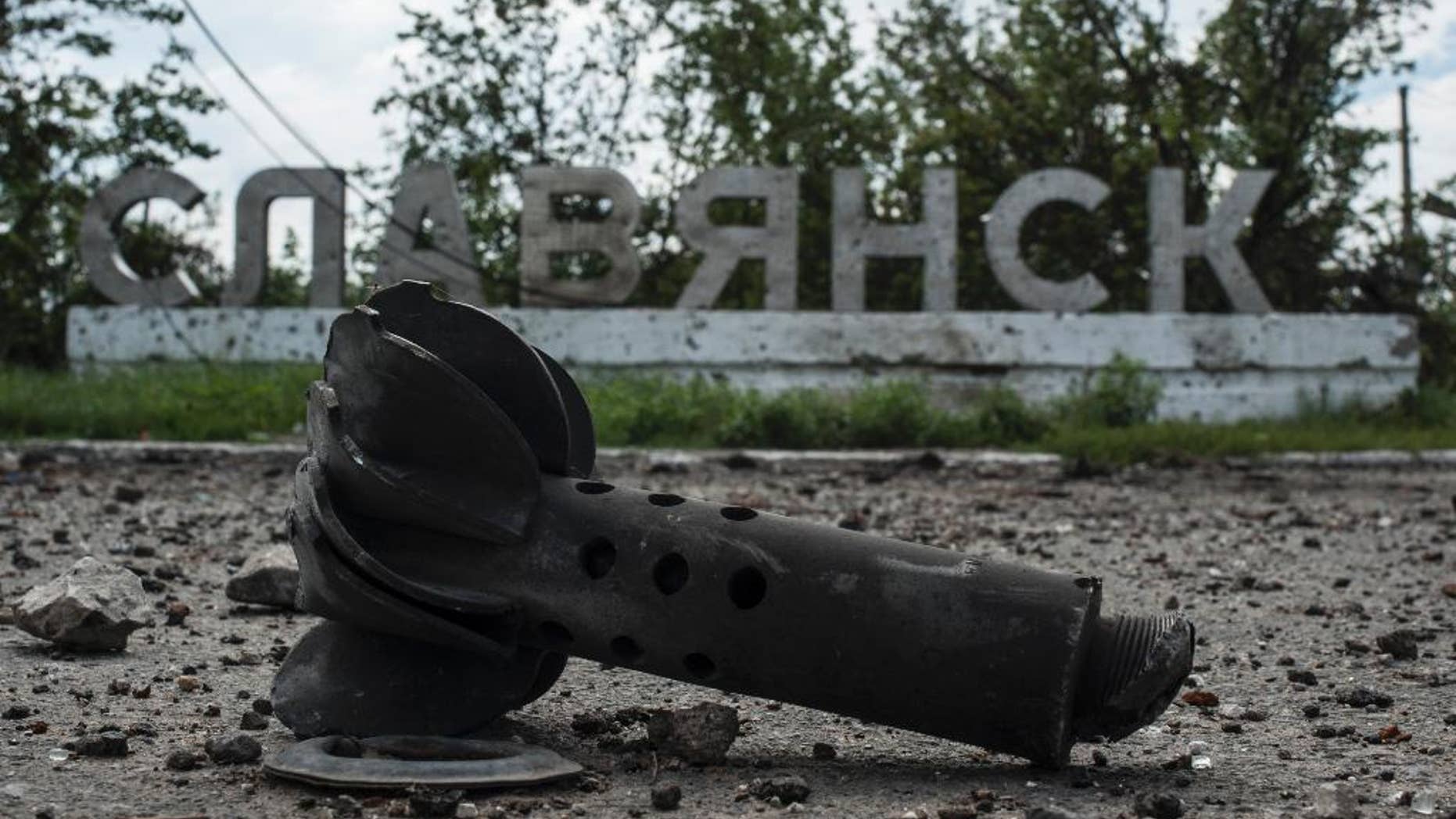 A part of the mortar shell is seen in front of a sign that reads 'Slovyansk', after heavy fighting between pro-Russian fighters and Ukrainian government troops just outside Slovyansk, eastern Ukraine, Wednesday, July 9, 2014. The rebels fled Slovyansk, a city of 100,000 that had been their stronghold, over the weekend as Ukrainian troops mounted an offensive. They left behind a city heavily damaged by fighting and riven by vehemently differing views. (AP Photo/Evgeniy Maloletka)