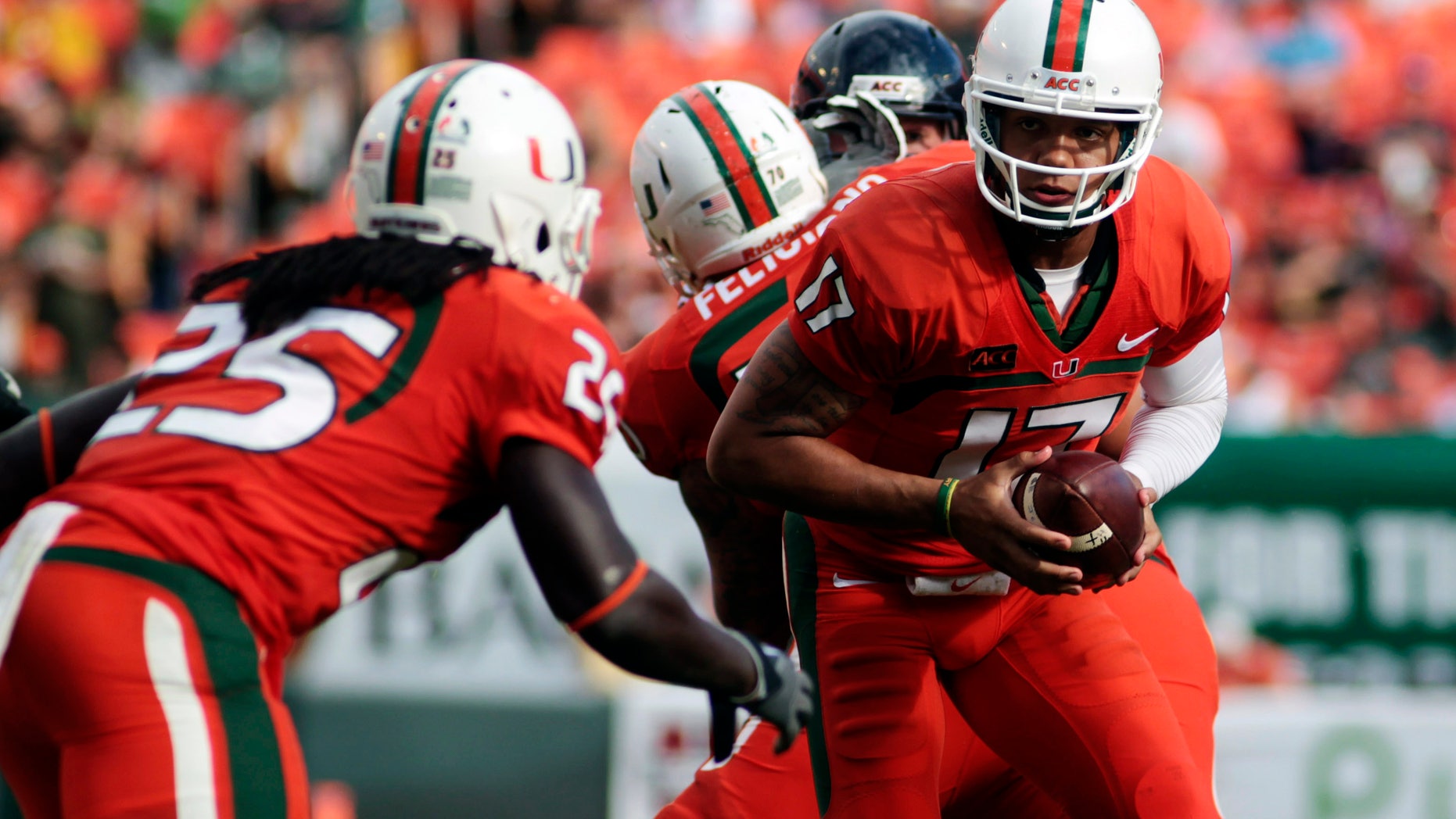 Miami's Stephen Morris (17) hands off to Dallas Crawford (25) during the second half of an NCAA college football game against Virginia in Miami Gardens, Fla., Saturday, Nov. 23, 2013. (AP Photo/J Pat Carter)