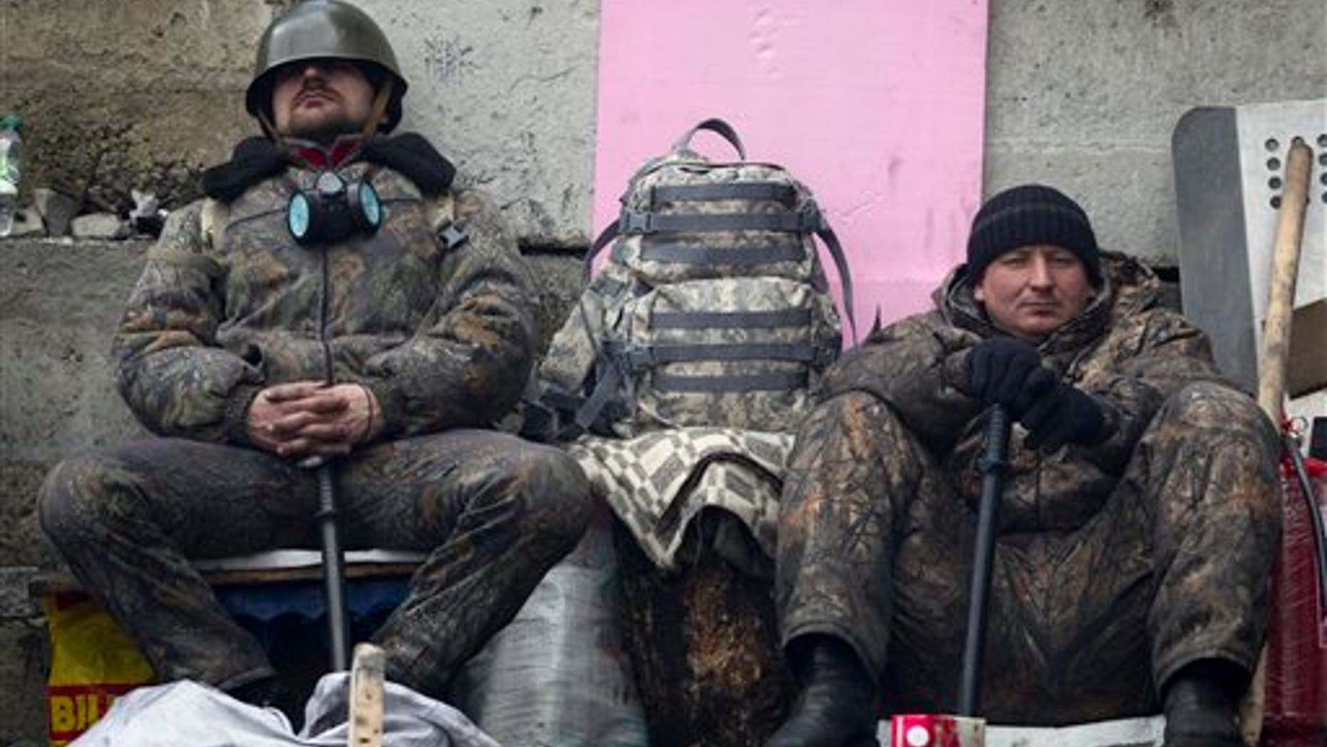 Anti-government protesters rest as they man a barricade in central Kiev, Ukraine, Friday, Feb. 21, 2014. European officials say Ukrainian protesters have agreed to a deal with Ukraine's president on defusing a deadly political crisis. Earlier Friday President Viktor Yanukovych announced early elections and promised to invite the opposition into the government. (AP Photo/Darko Bandic)