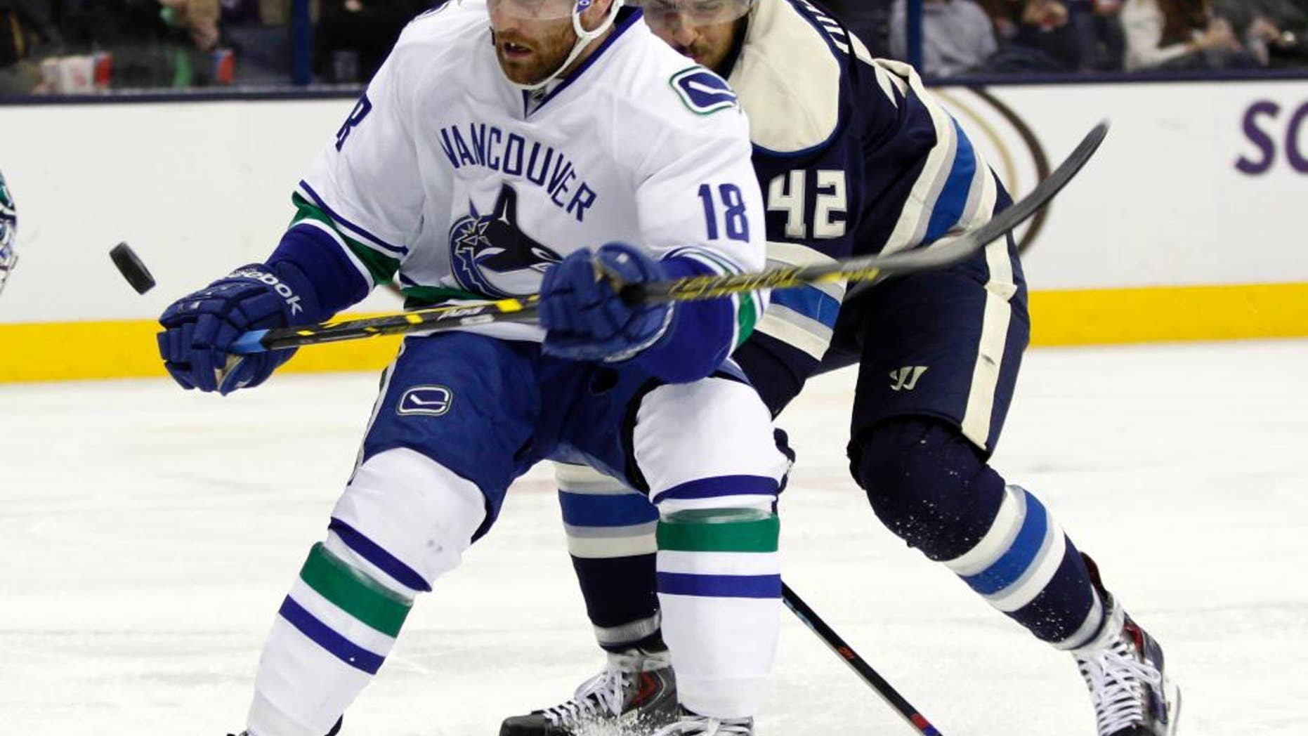 Vancouver Canucks' Ryan Stanton, left, works for the puck in front of Columbus Blue Jackets' Artem Anisimov, of Russia, during the second period of an NHL hockey game in Columbus, Ohio, Friday, Nov. 28, 2014. (AP Photo/Paul Vernon)