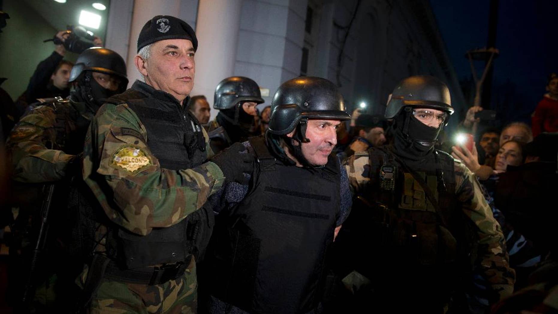 Former Public Works Secretary Jose Lopez, center, is escort by police outside the police station in the outskirts of Buenos Aires, Argentina, Tuesday, June 14, 2016. Lopez, an official in the former government of President Fernandez was arrested on Tuesday while trying to hide millions in cash and jewels in a monastery, captivating Argentina in what the cabinet chief said seems more like the plot of a Hollywood movie. (AP Photo/Natacha Pisarenko)