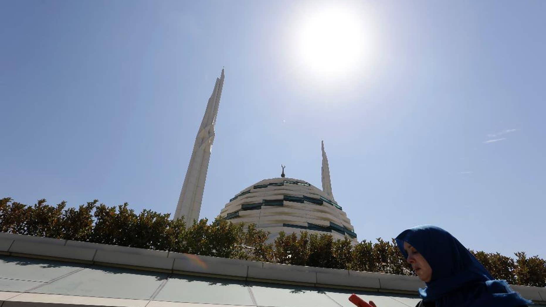 A woman checks her cell phone as she passes outside Marmara University Theological School mosque in Istanbul, Friday, Aug. 19, 2016. Turkey accuses U.S.-based cleric Fethullah Gulen of masterminding the July 15th coup and has launched a massive crackdown on his movement, detaining more than 40,000 people and dismissing tens of thousands from government jobs. (AP Photo/Thanassis Stavrakis)