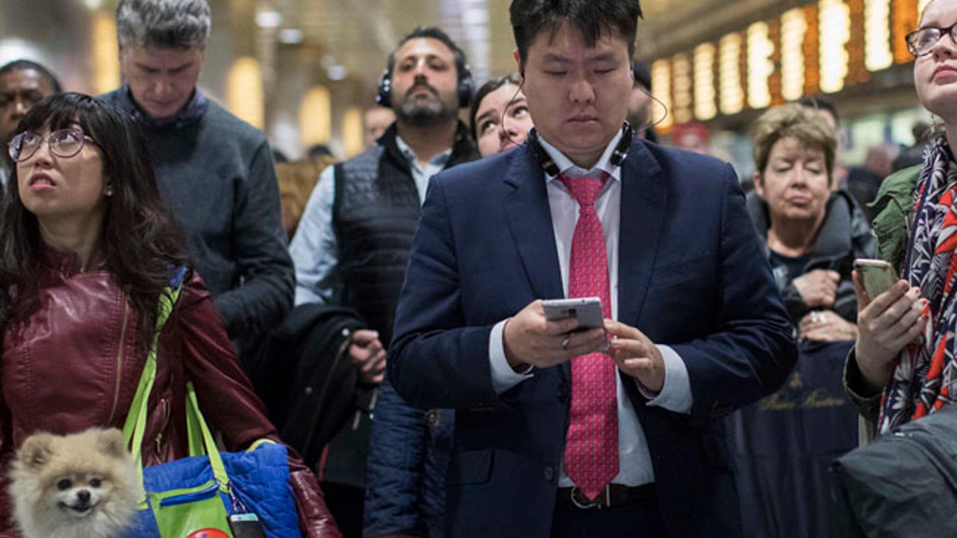 Evening rush hour commuters inspect the departures information board while they wait for their respective Long Island Rail Road trains at Penn Station, Friday, March 24, 2017, in New York. Commuters to both New Jersey and Long Island faced a difficult journey home Friday evening after two passenger trains clipped each other during the morning rush at Penn Station, jolting riders and creating major travel disruptions, but causing no serious injuries. (AP Photo/Mary Altaffer)