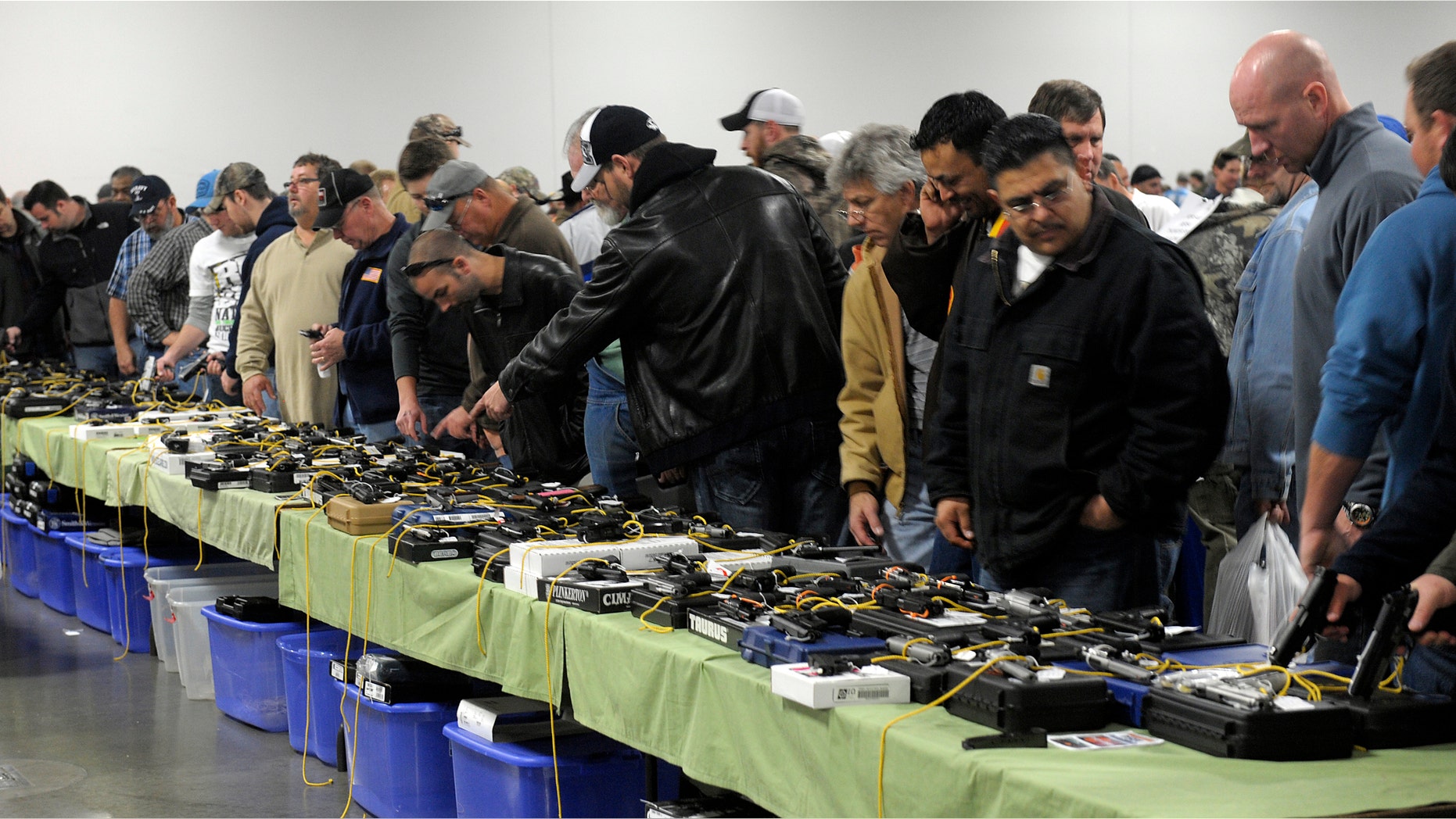 FILE: Dec. 22, 2012: People look over a table of handguns for sale at a gun show in Kansas City, Missouri.