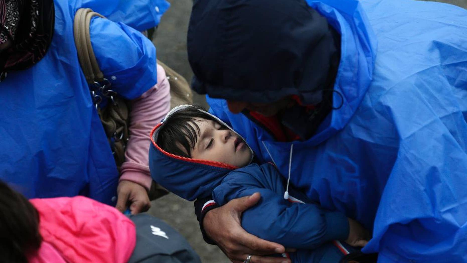 FILE - In this Sept. 24, 2015 file photo a man carries a child to board a train at a station near the village of Zakany, Hungary. UNICEF, the United Nations’ children’s agency, says it is alarmed by the new Hungarian law allowing the detention of all asylum seekers, including unaccompanied children older than 14, in border camps made of shipping containers. (AP Photo/Petr David Josek, file)