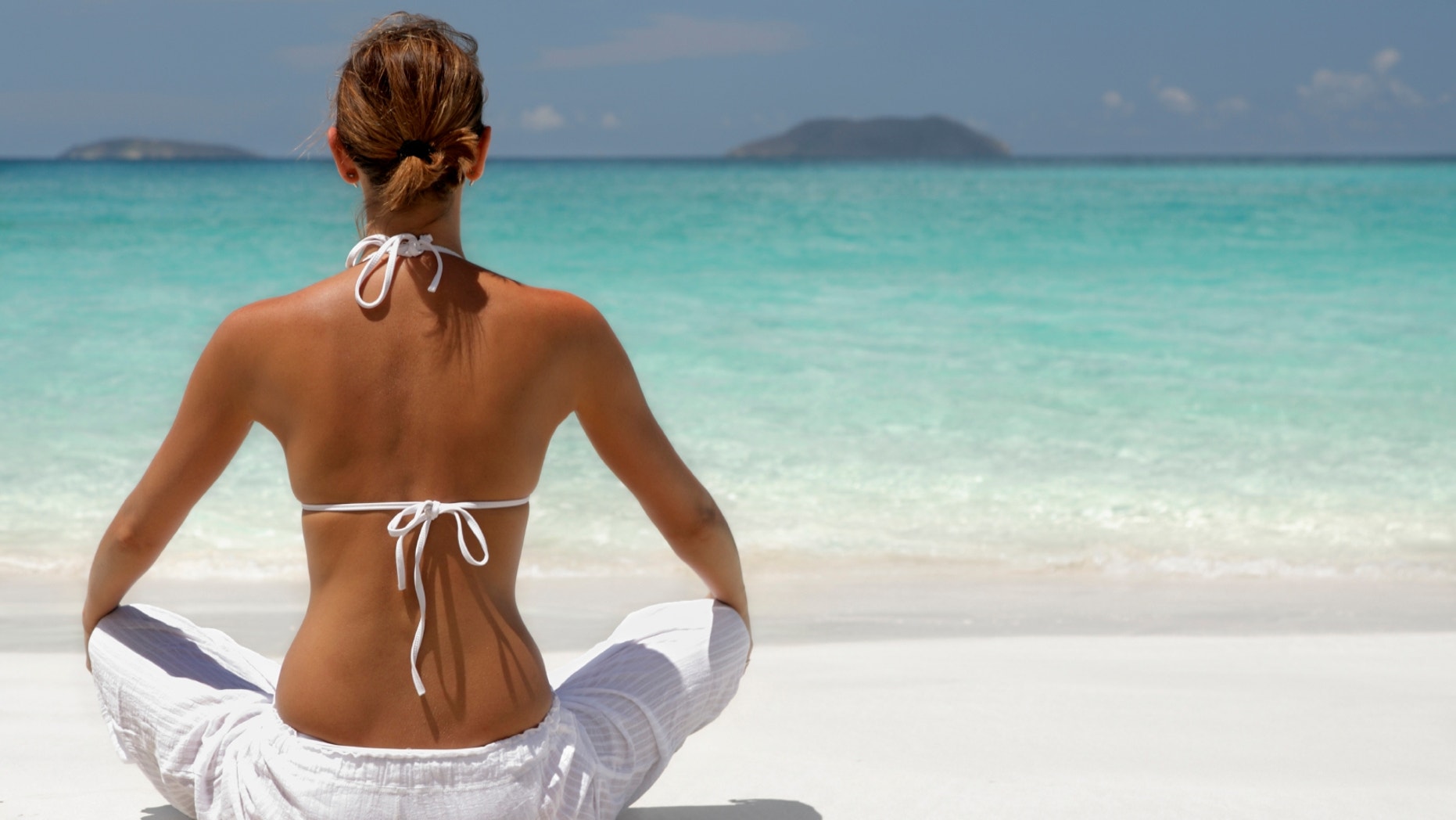 woman meditating on tropical beach in the caribbean